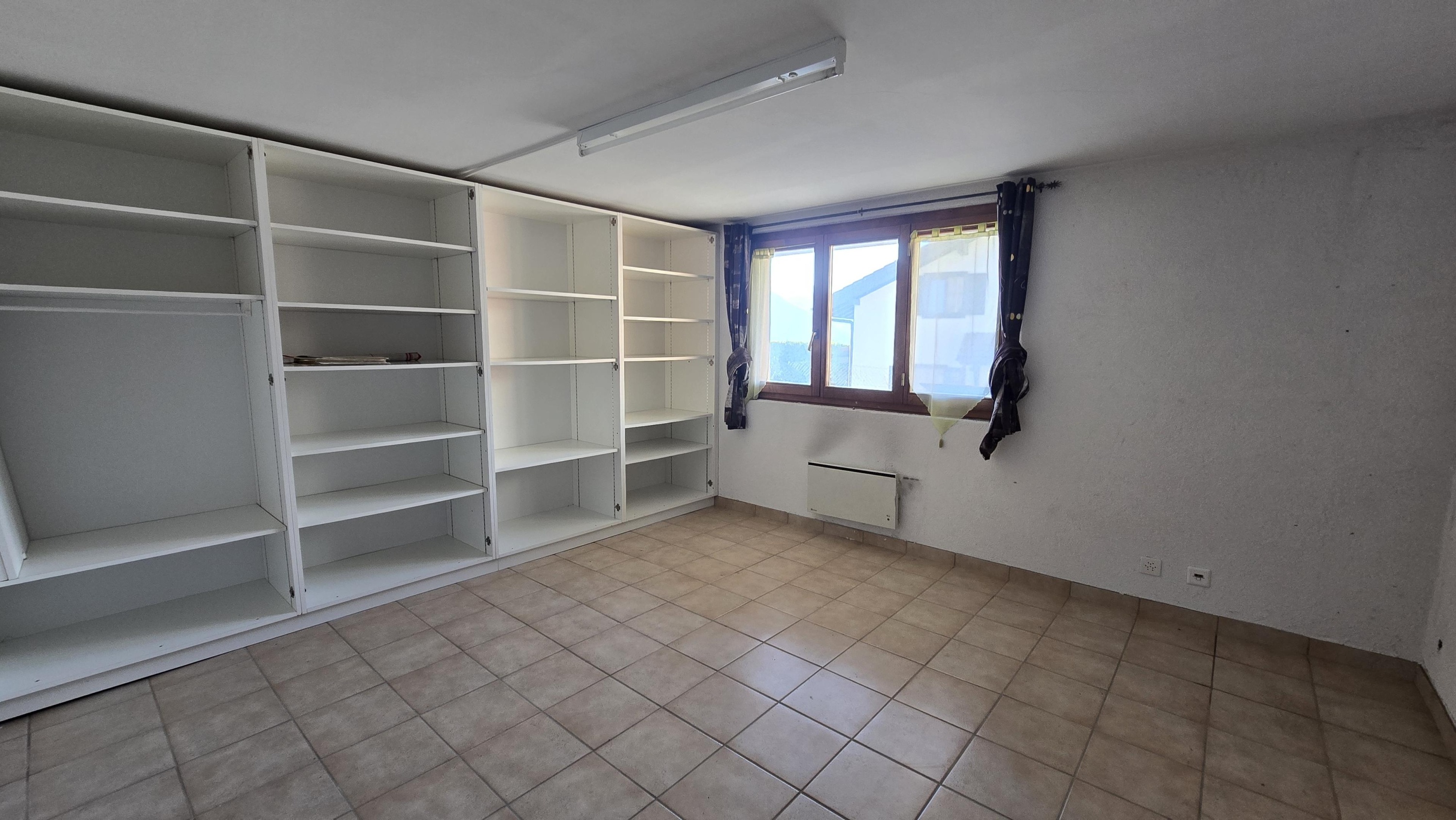 Leerer Raum mit Einbauregalen und Fenster