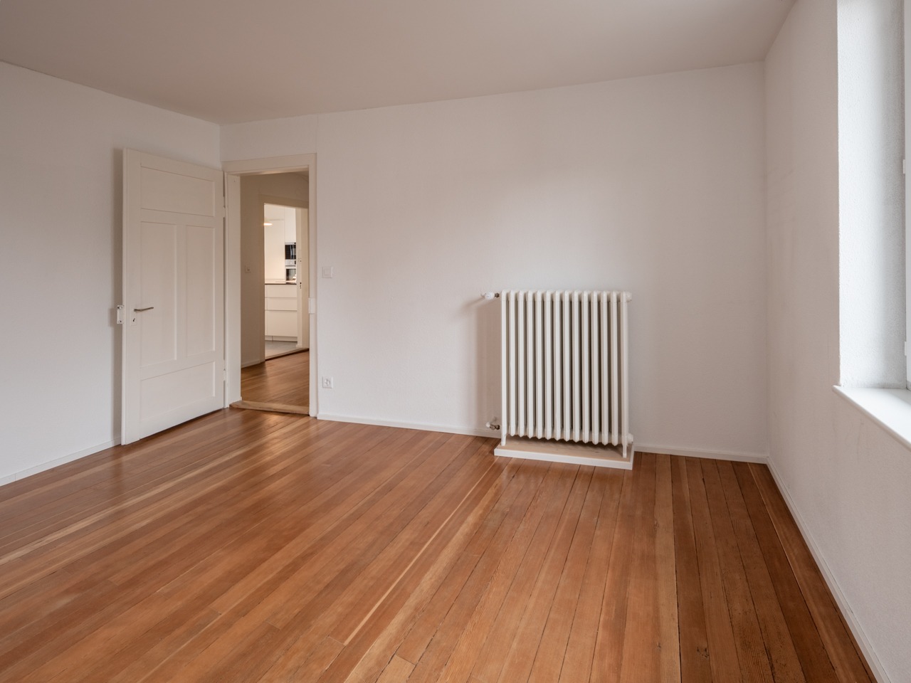 Leerer Wohnraum mit Holzboden und Heizkörper