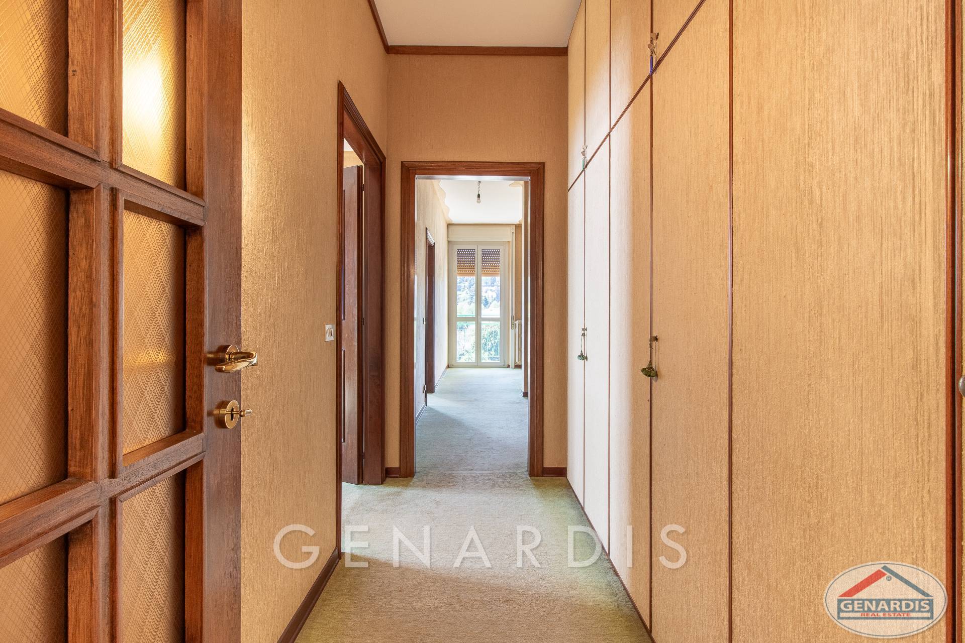 Flur mit Einbauschrank und Blick in einen hellen Durchgang