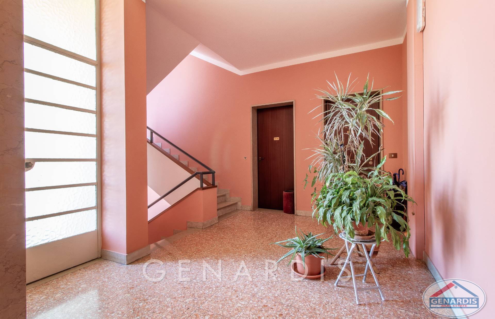 Treppenhaus mit rosa Wänden und Pflanzen