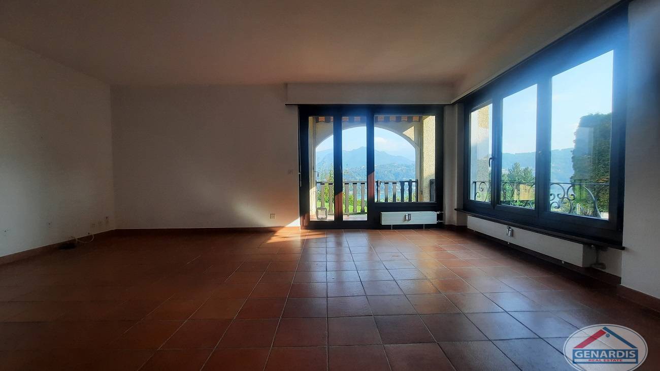 Leerer Wohnraum mit großem Panoramafenster und Balkonzugang
