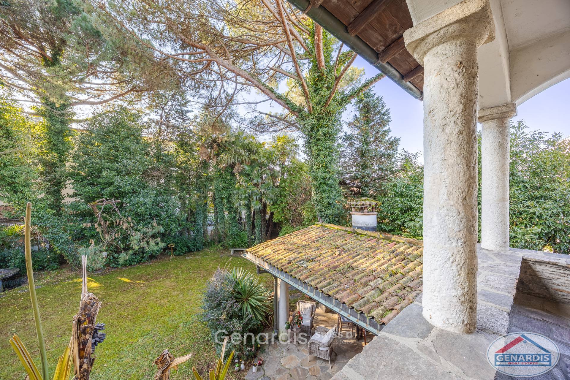 Blick in einen grünen Garten von einer überdachten Terrasse