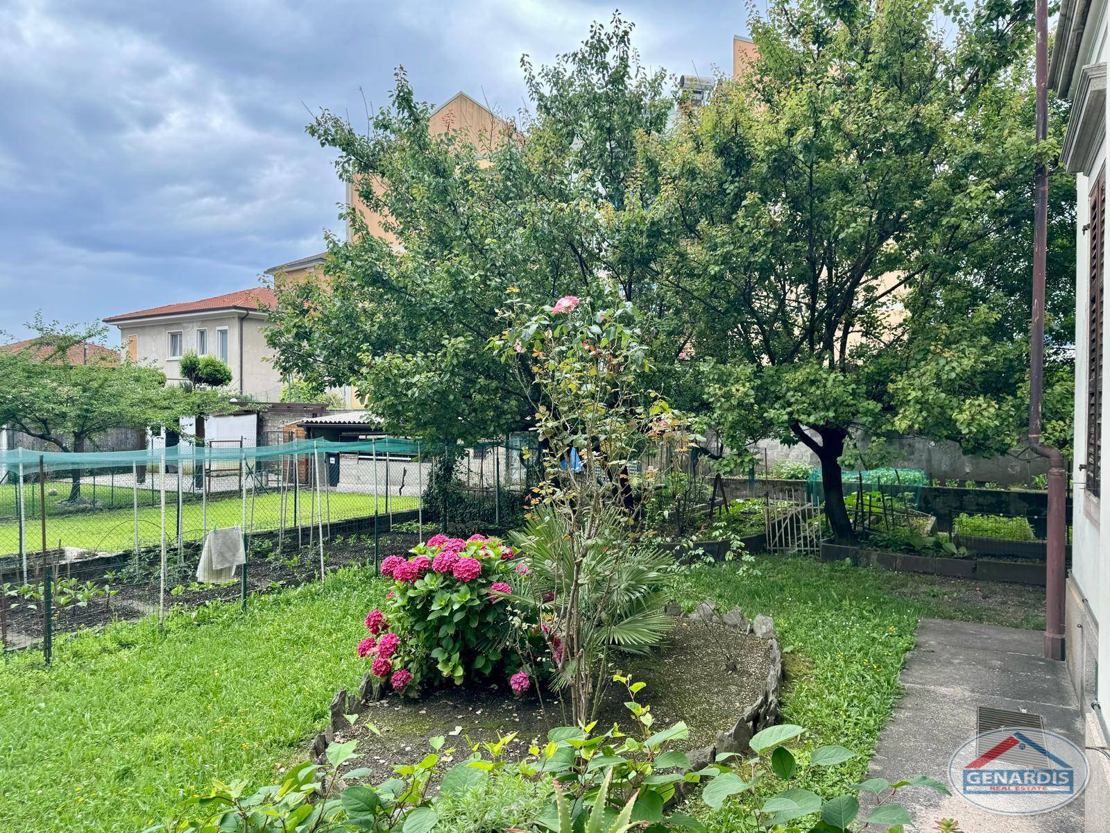 Garten mit Bäumen und Blumenbeet