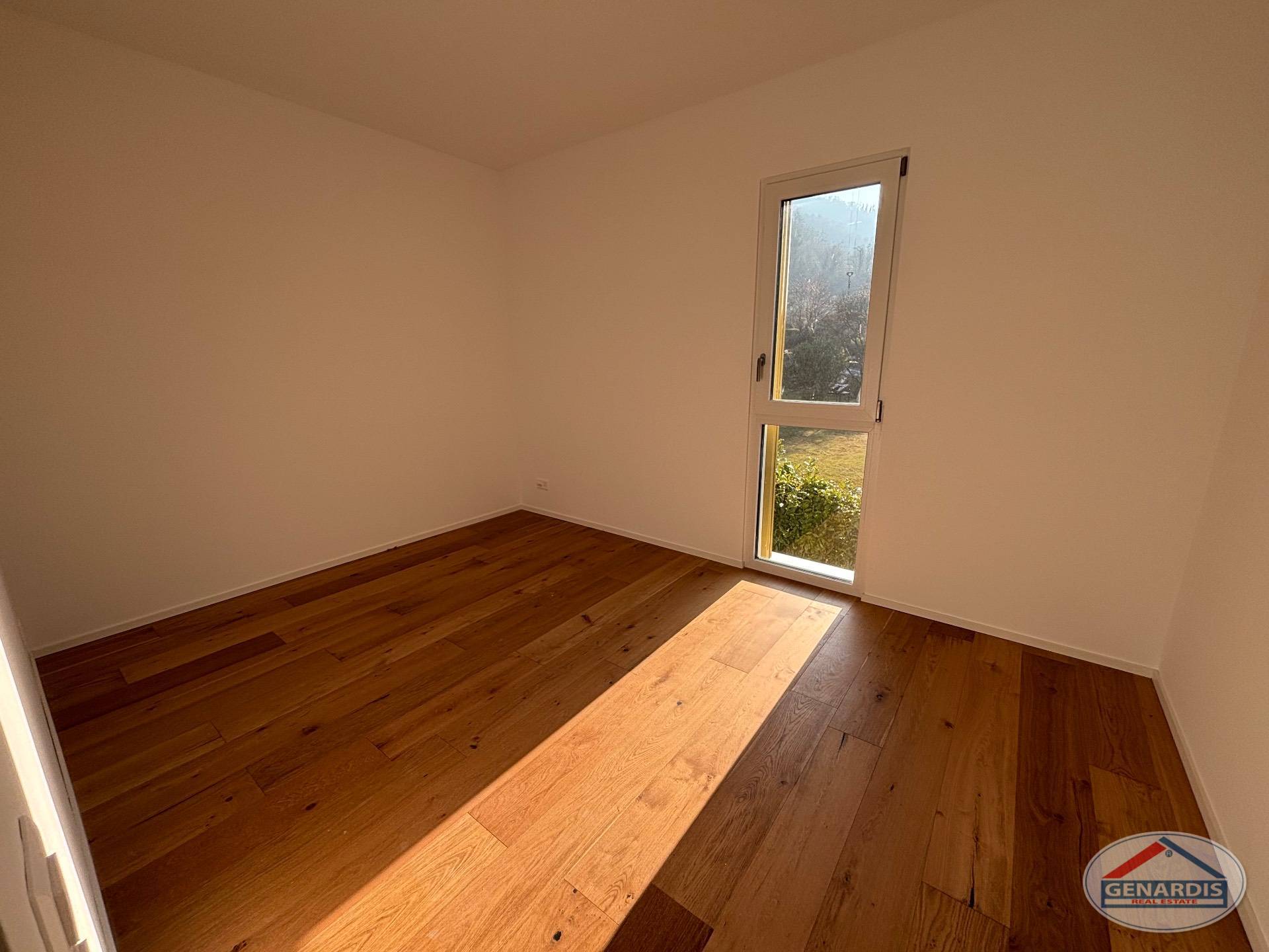Leerer, heller Raum mit Holzboden und schmalem Fenster