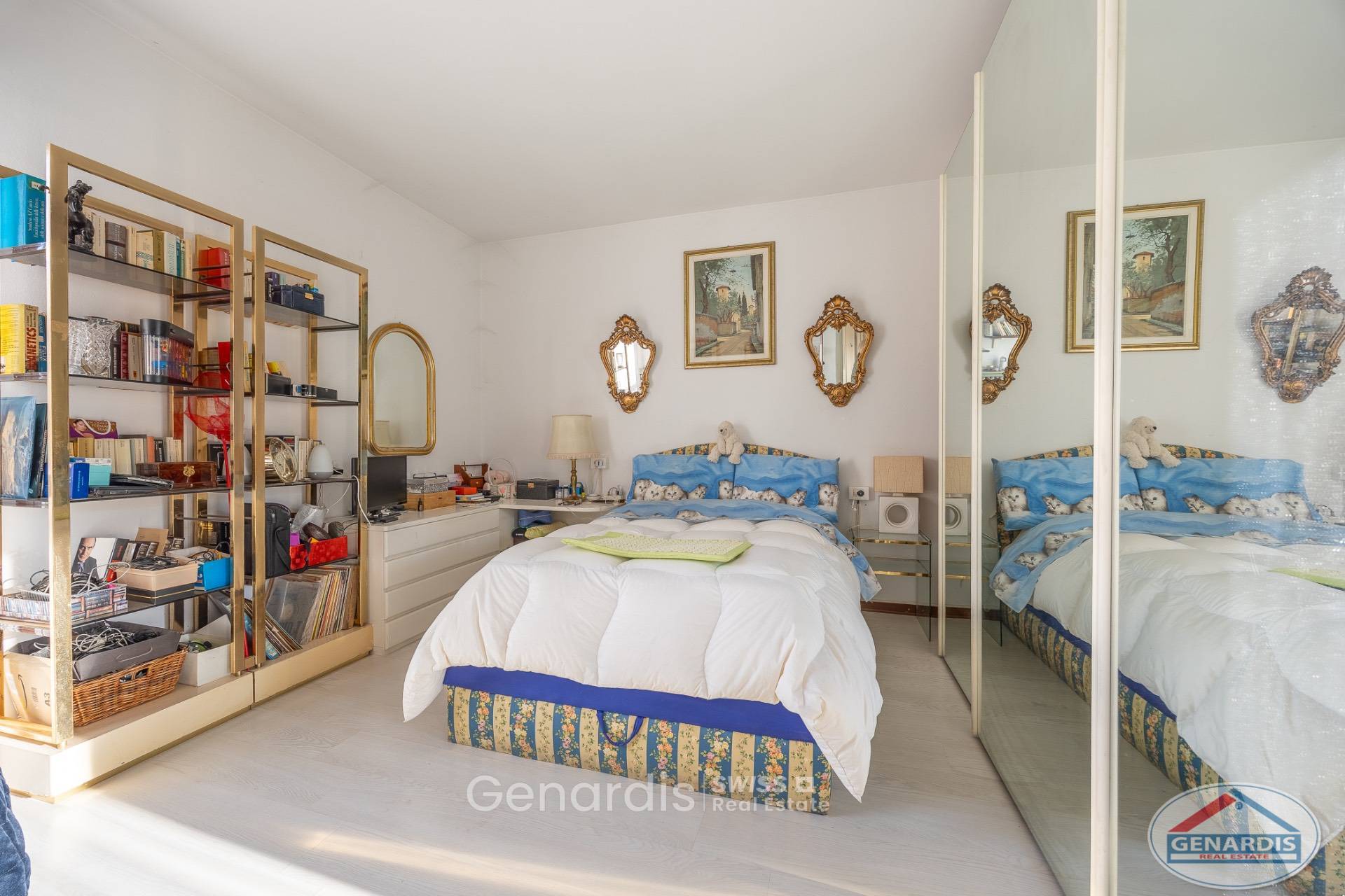 Schlafzimmer mit goldfarbenen Regalen und Spiegelschrank