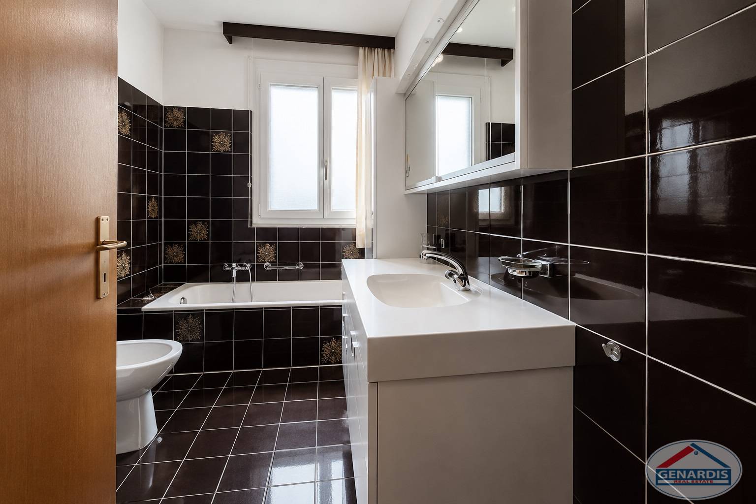 Badezimmer mit dunklen Fliesen und Badewanne