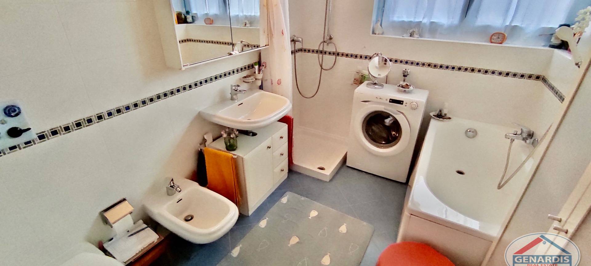 Badezimmer mit Badewanne, Dusche und Waschmaschine