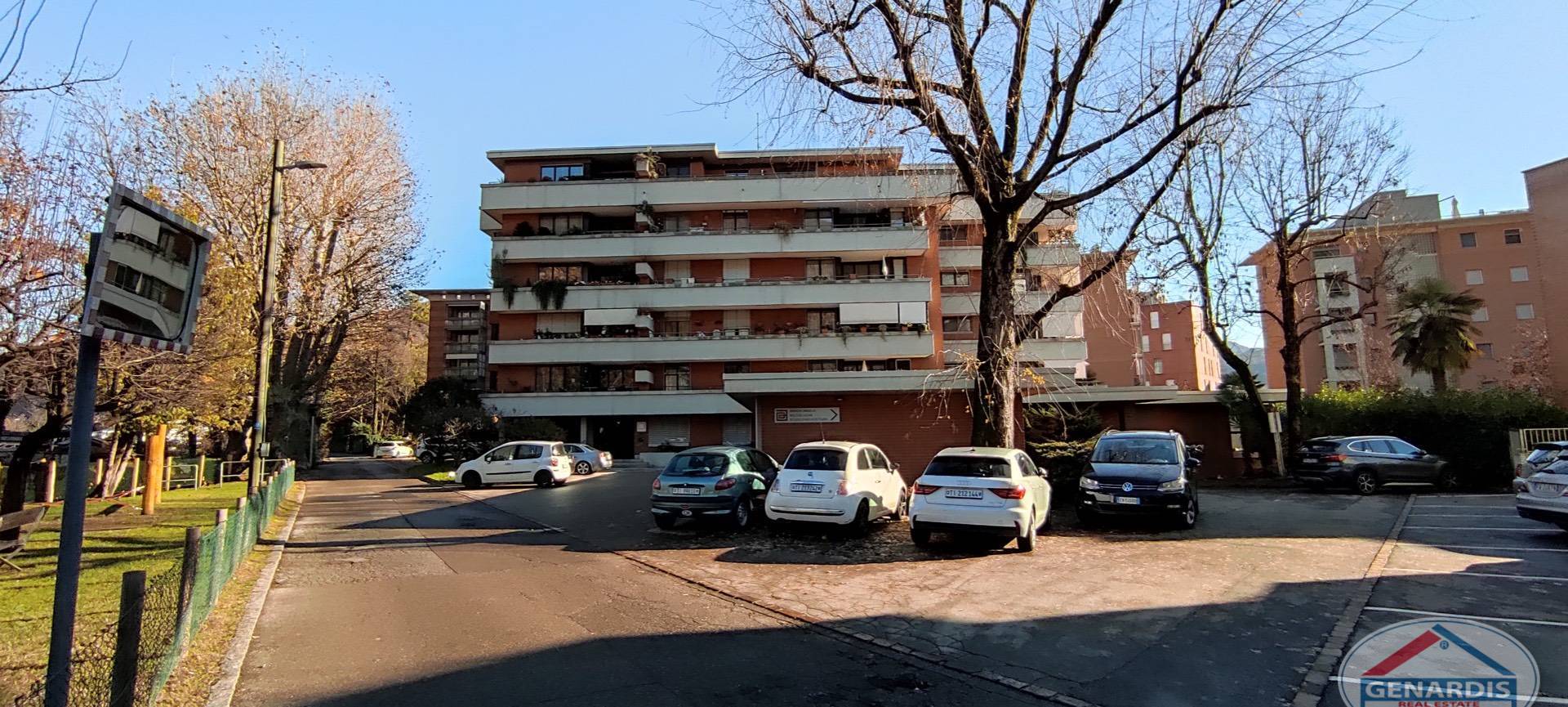 Mehrfamilienhaus mit Parkplatz und Bäumen