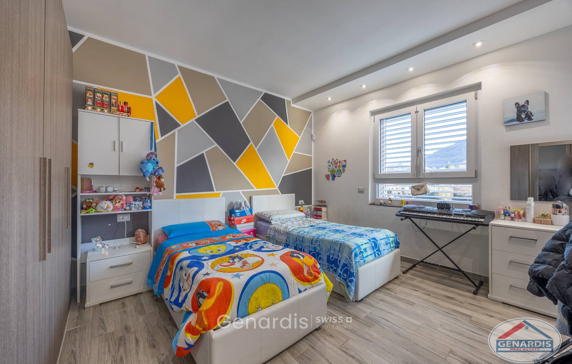 Kinderzimmer mit zwei Betten und geometrischer Akzentwand