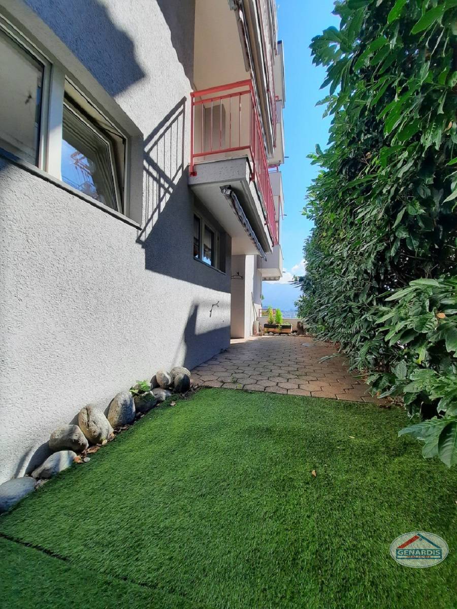 Außenansicht eines schmalen seitlichen Zugangs mit Balkon und Grünstreifen