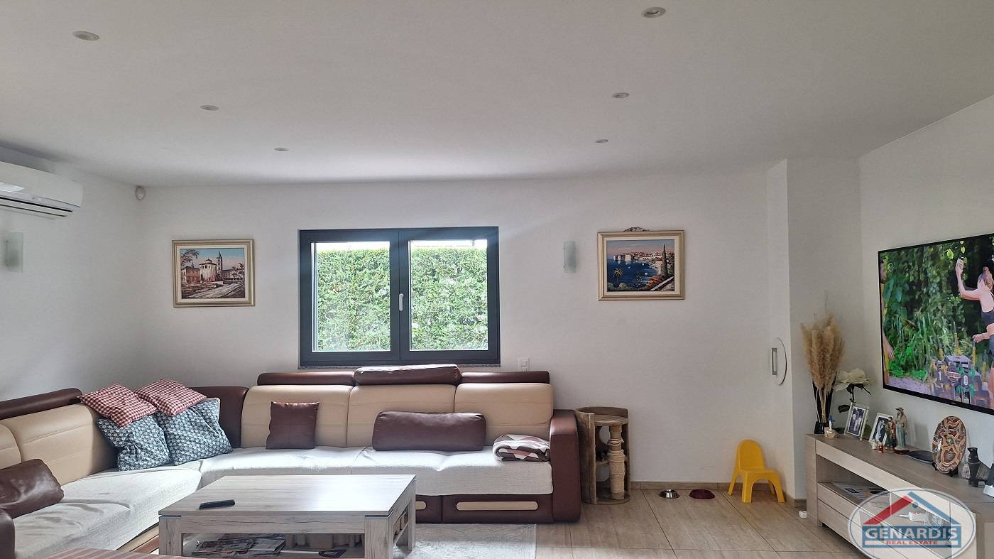 Helles Wohnzimmer mit Fenster, Sofa und TV-Wand