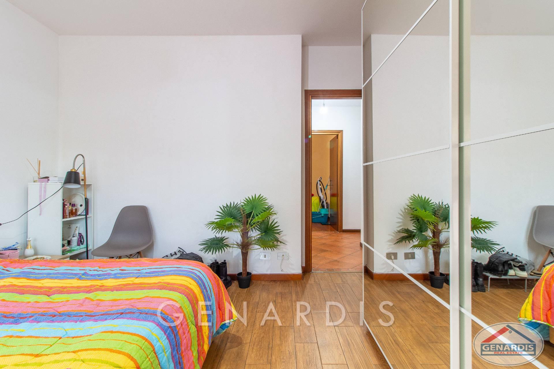 Helles Schlafzimmer mit Holzoptikboden und Spiegelkleiderschrank