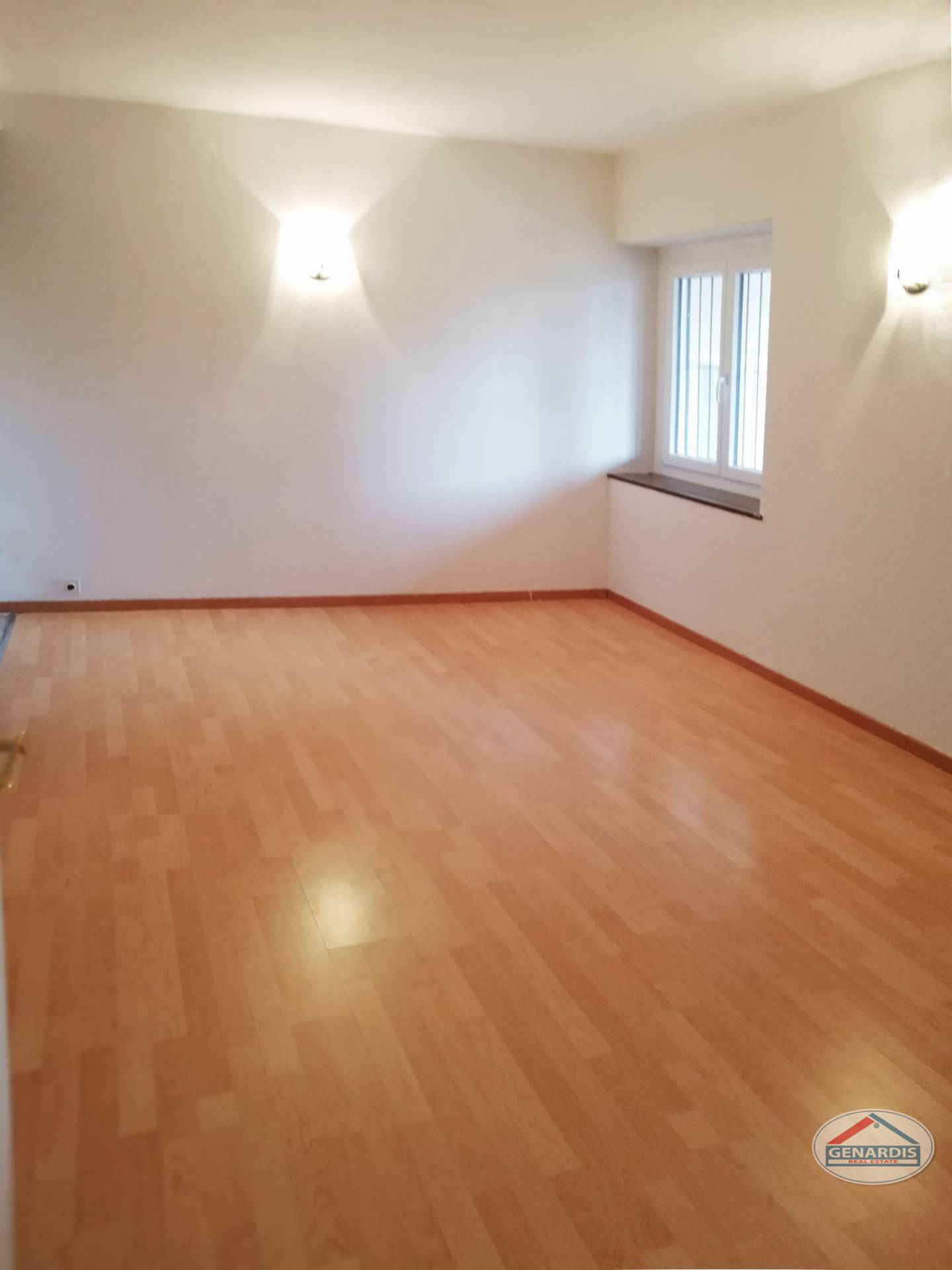 Leerer Wohnraum mit Parkettboden und Fenster