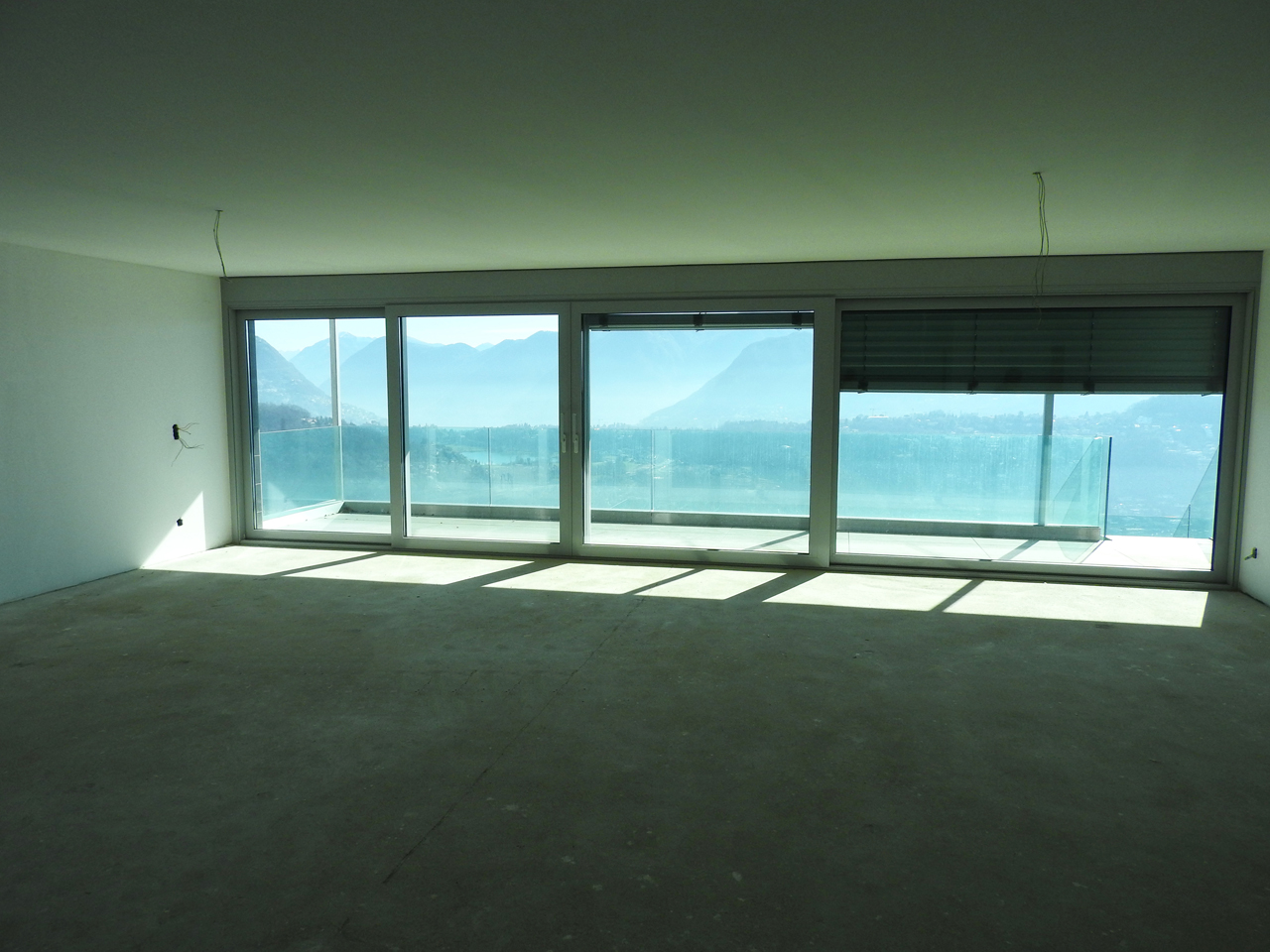 Leerer Wohnraum mit Panoramafenstern und Bergblick