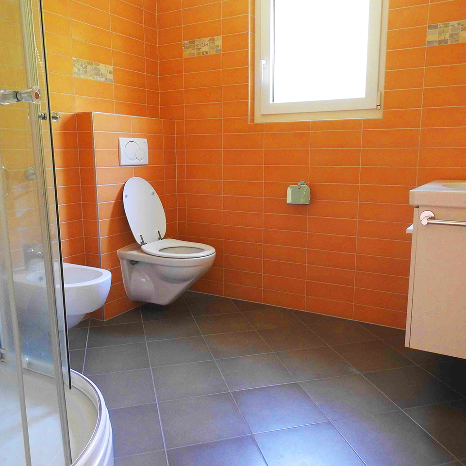 Orangefarbenes Badezimmer mit WC und Dusche