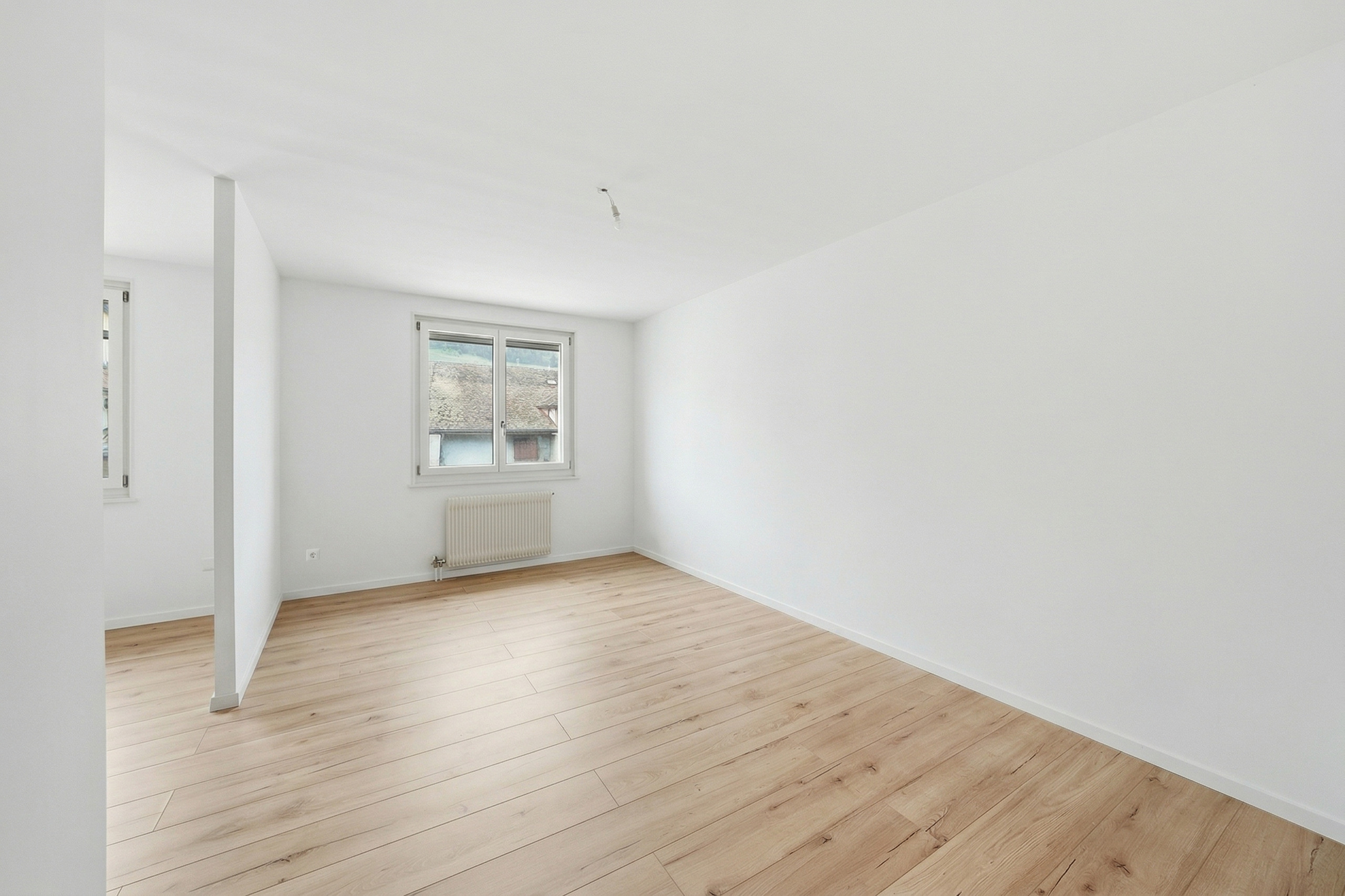 Heller leerer Raum mit Holzoptikboden und Fenster