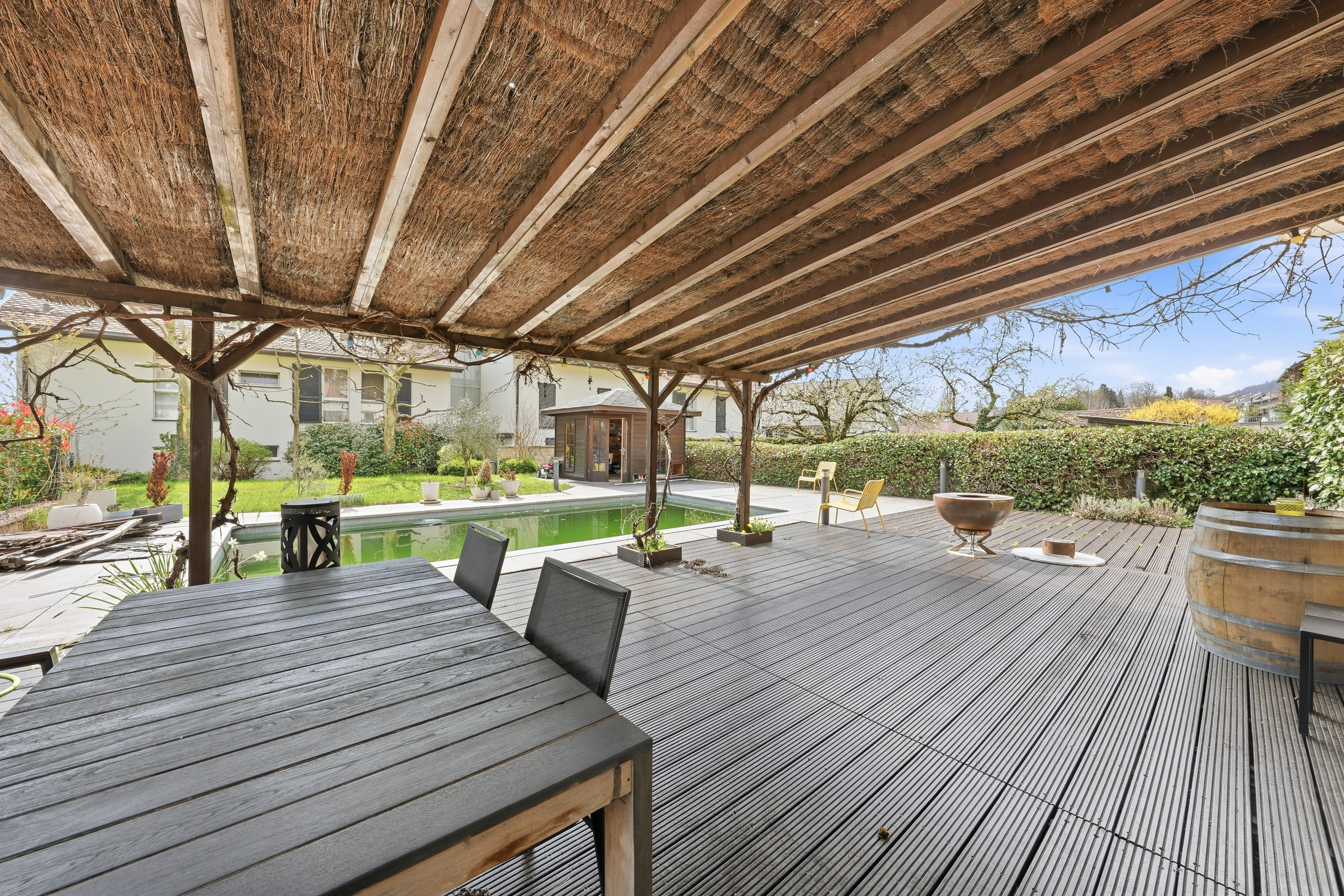 Überdachte Terrassenlounge mit Pool und Garten