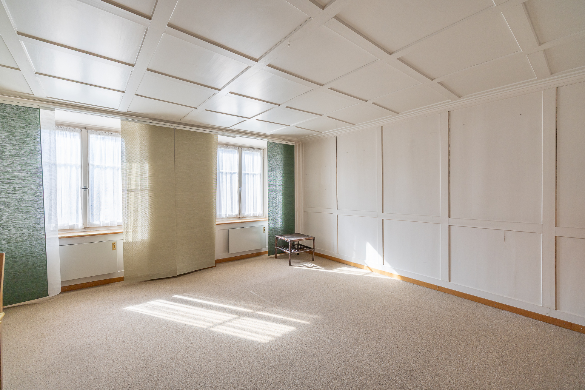 Heller leerer Raum mit Fensterfront und Paneelwänden