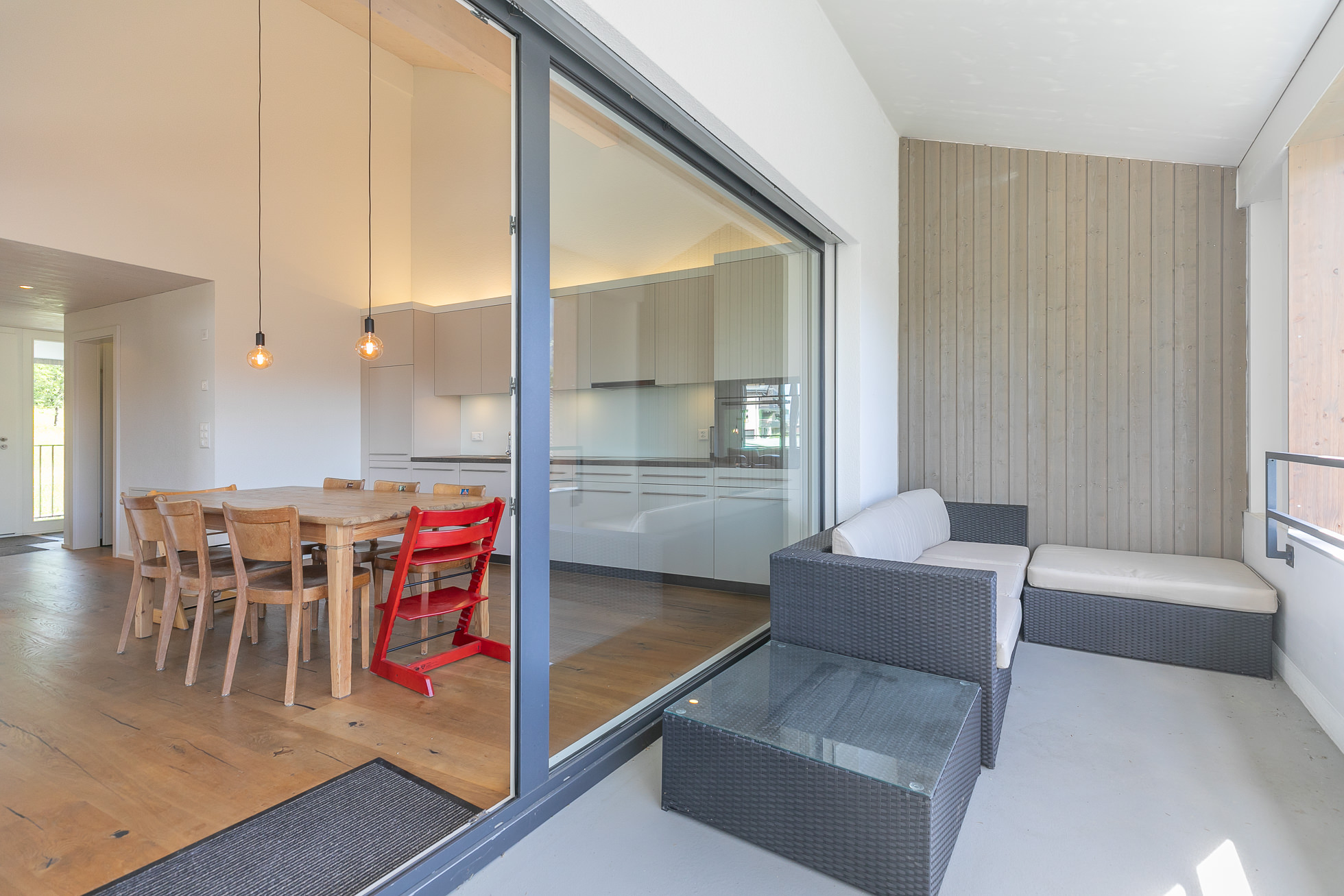 Überdachter Balkon mit Blick in den offenen Wohn- und Essbereich