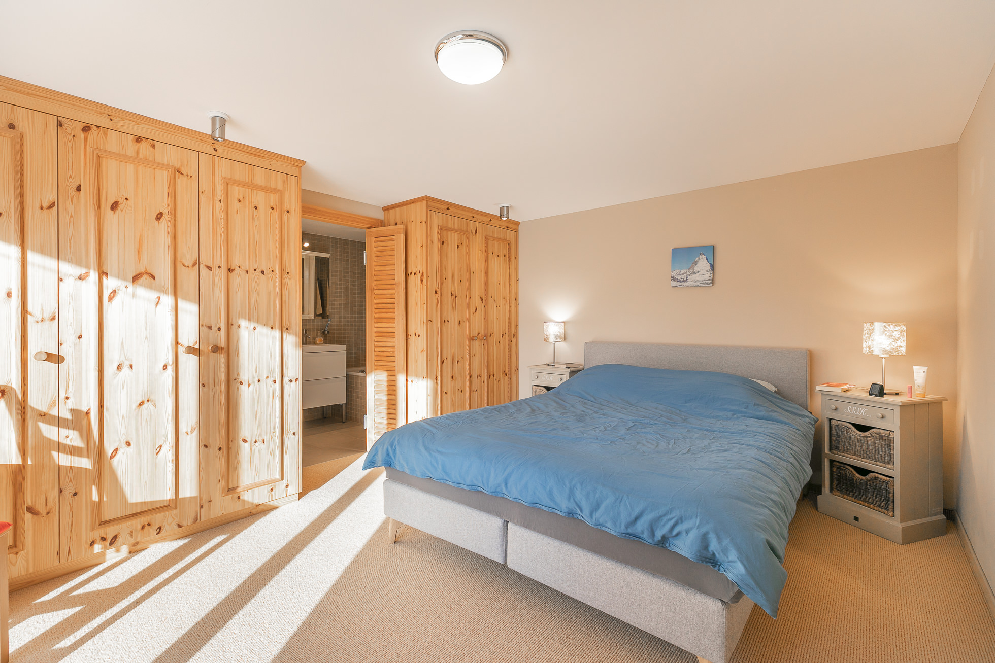 Helles Schlafzimmer mit Einbauschränken und Blick ins Bad