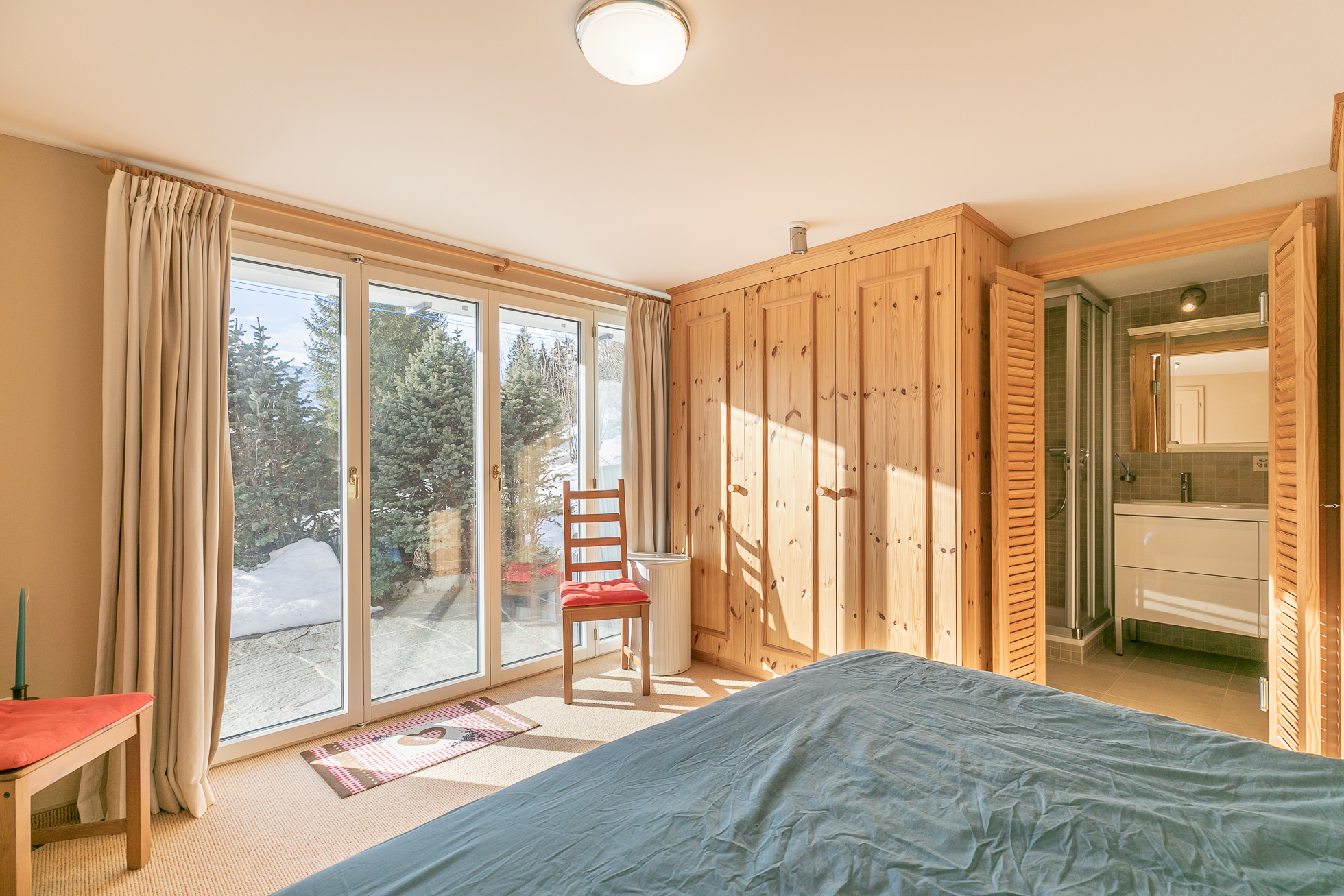 Helles Schlafzimmer mit Holzmöbeln und Blick ins Grüne