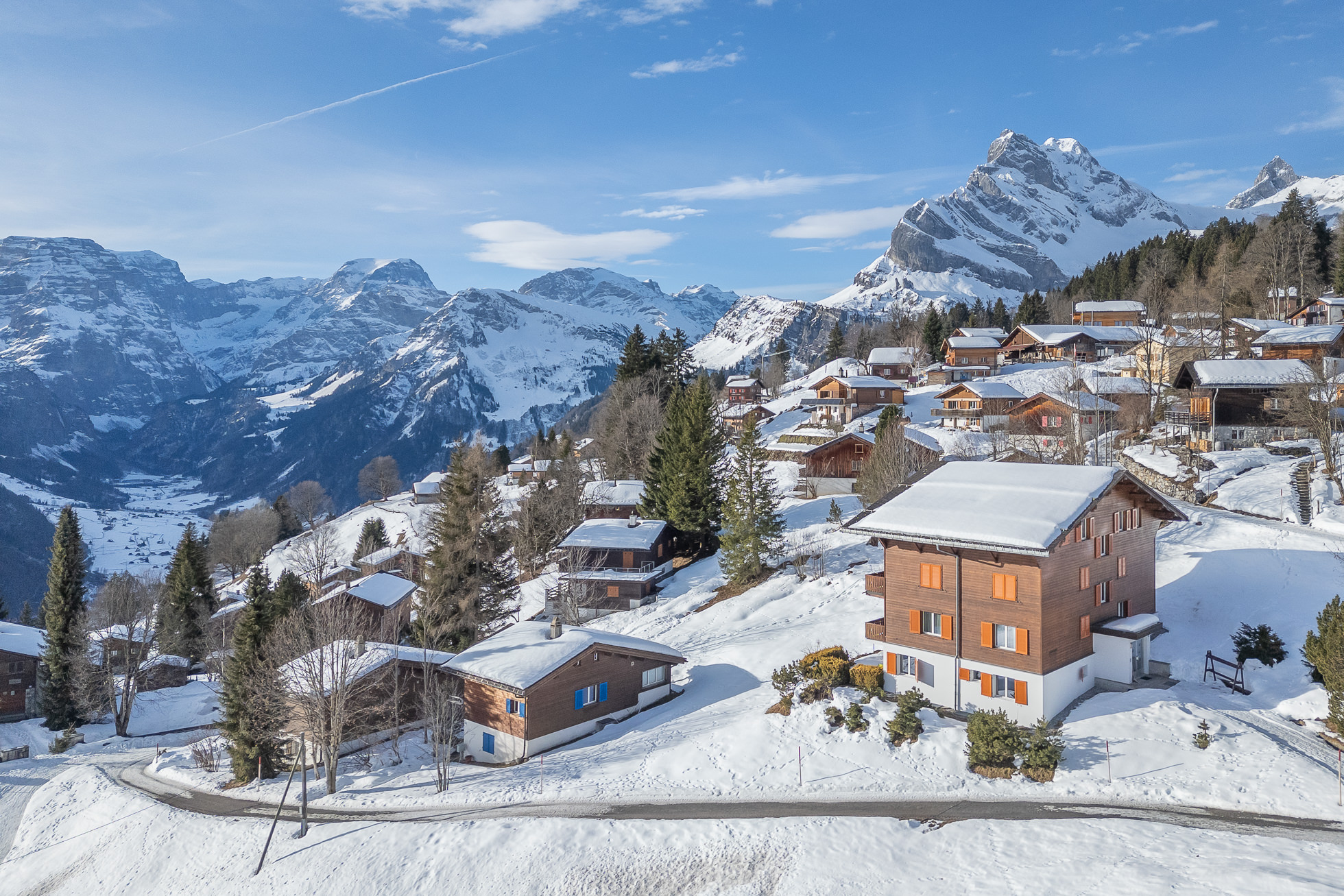 Verschneite Bergsiedlung mit Chalets und Panorama