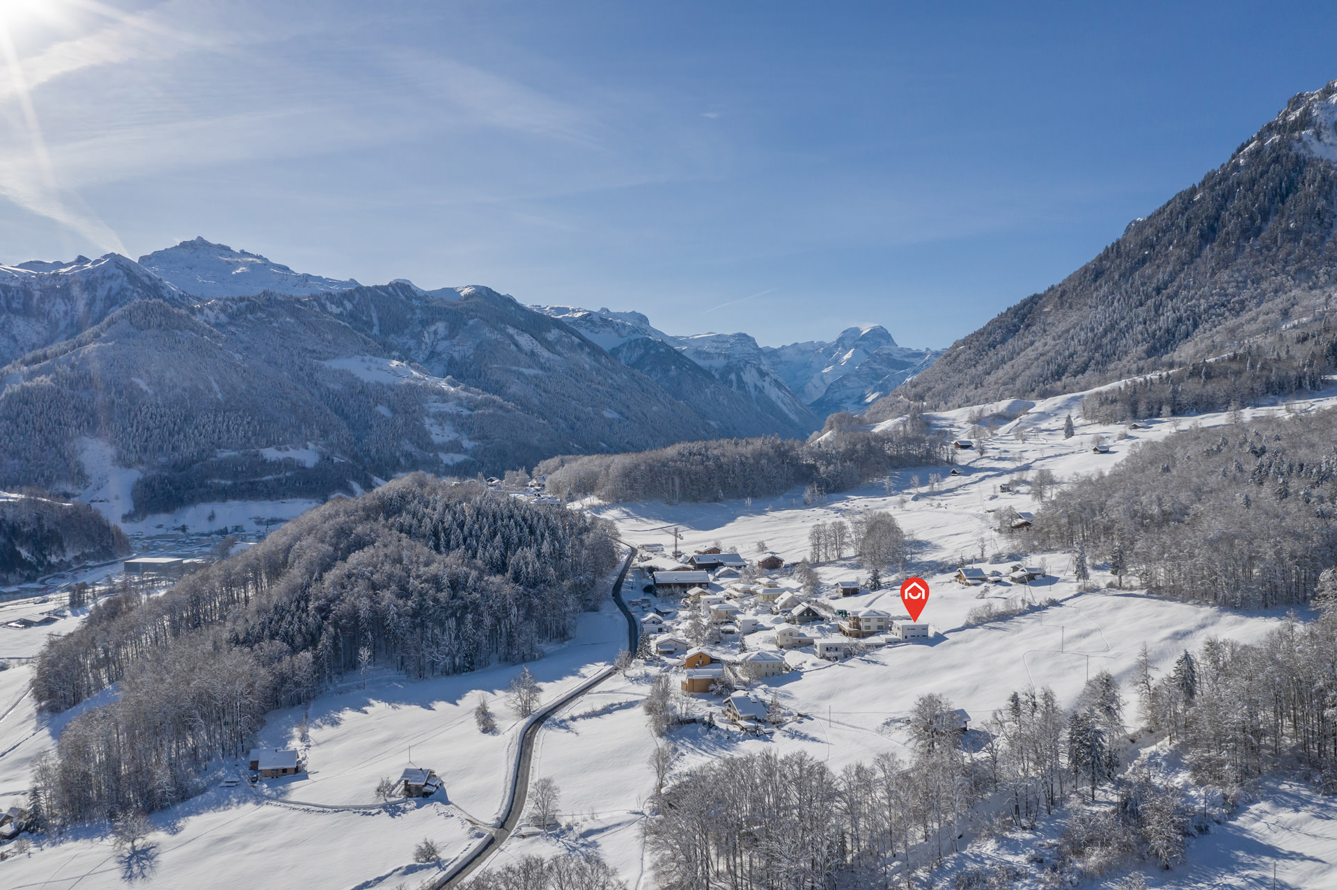 Schneebedeckte Berglandschaft mit Siedlung im Tal