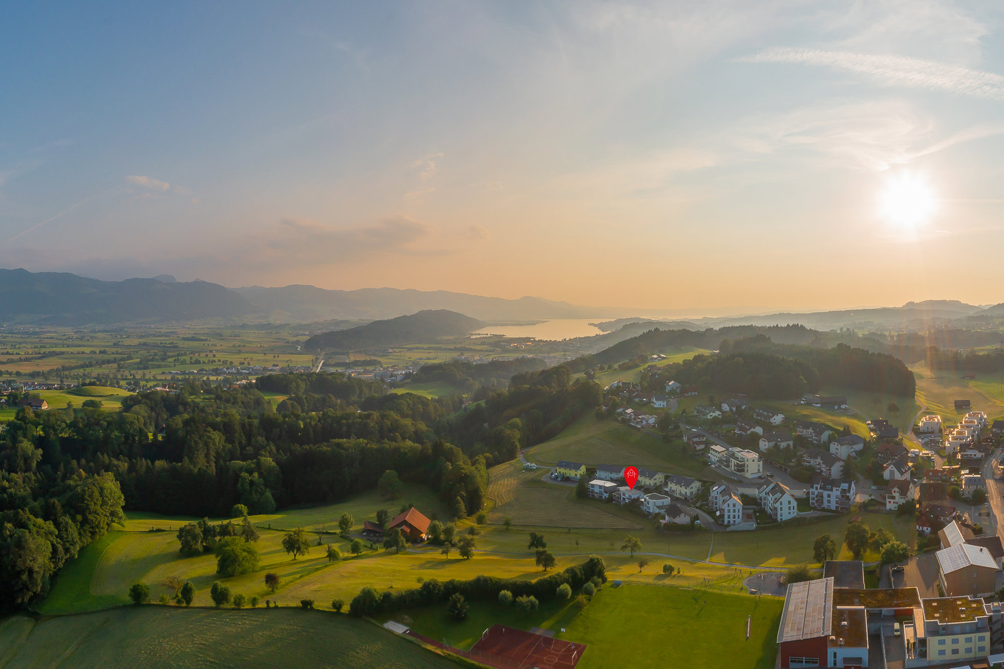 Luftaufnahme einer ländlichen Landschaft mit See und Siedlung bei Sonnenuntergang