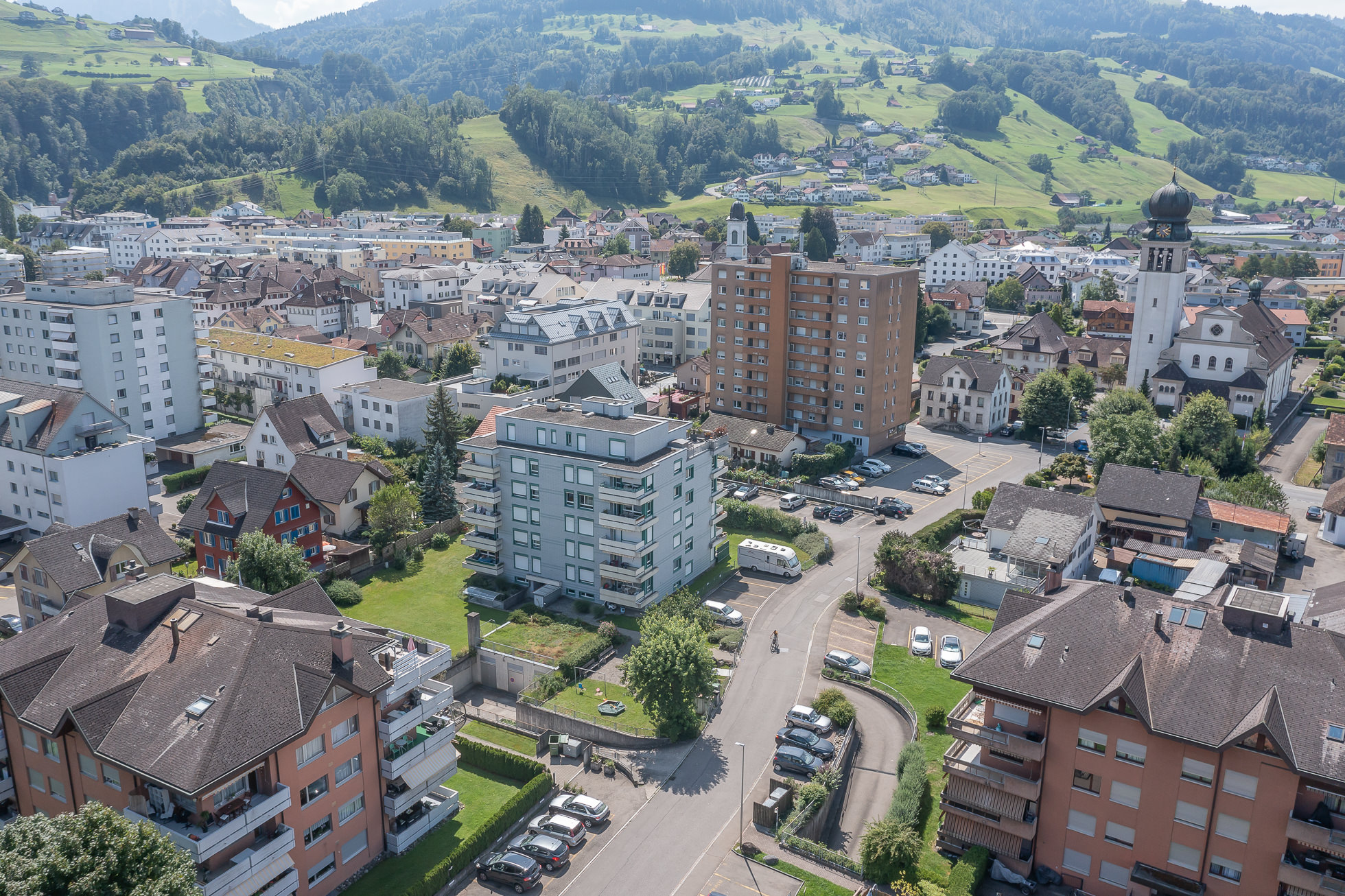 Luftaufnahme über einer Kleinstadt mit Alpenpanorama