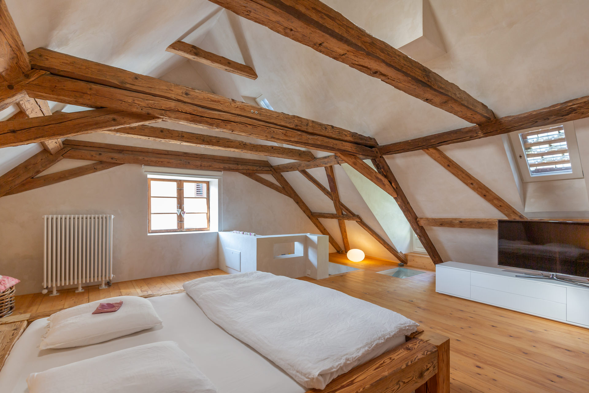 Dachgeschoss-Schlafzimmer mit sichtbaren Holzbalken