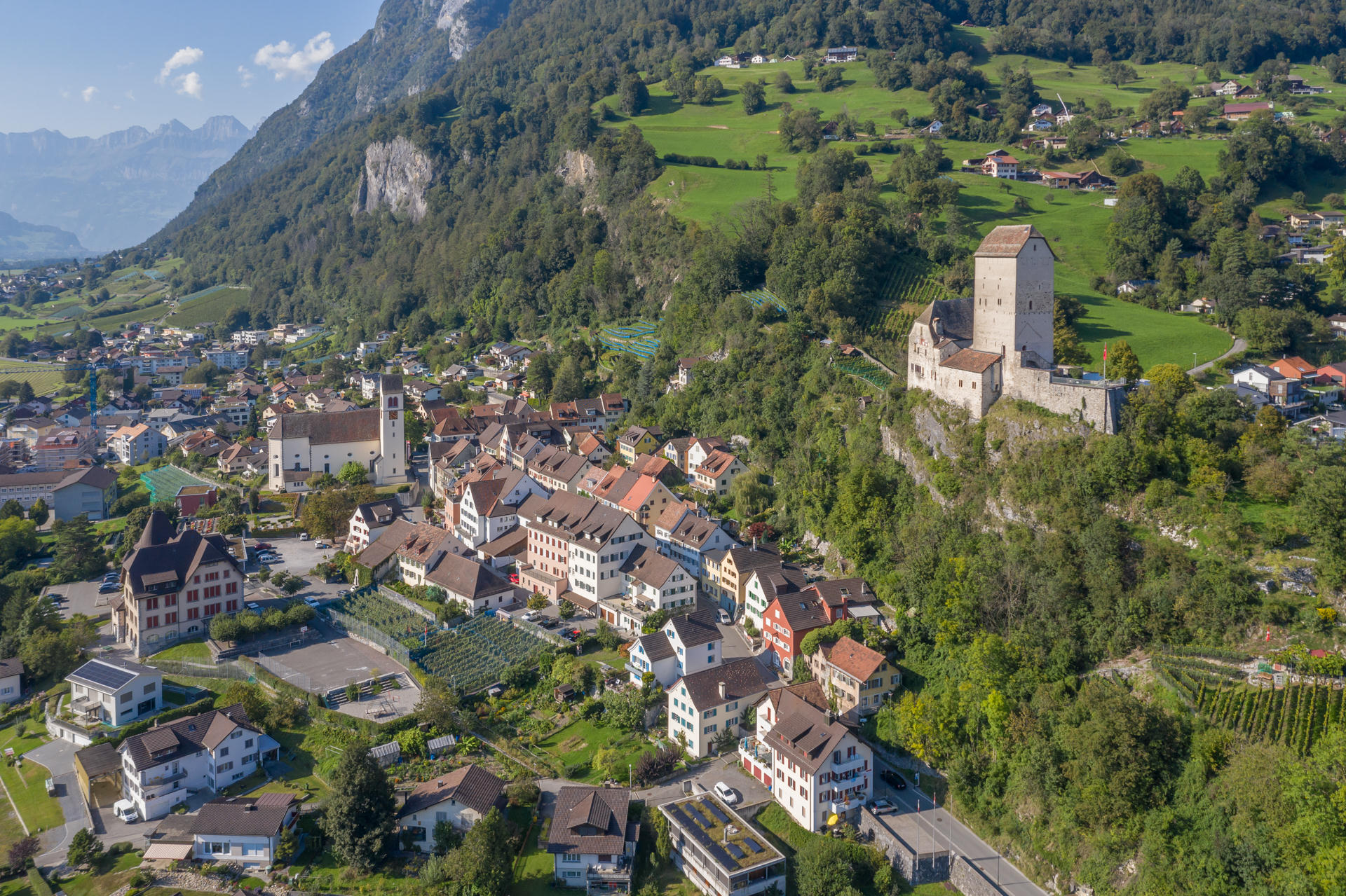 Luftaufnahme eines alpinen Ortes mit Burg und Kirche