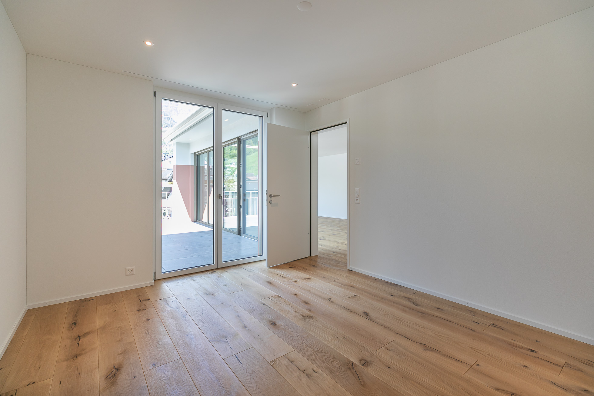 Heller leerer Raum mit Holzboden und Blick auf den Balkon