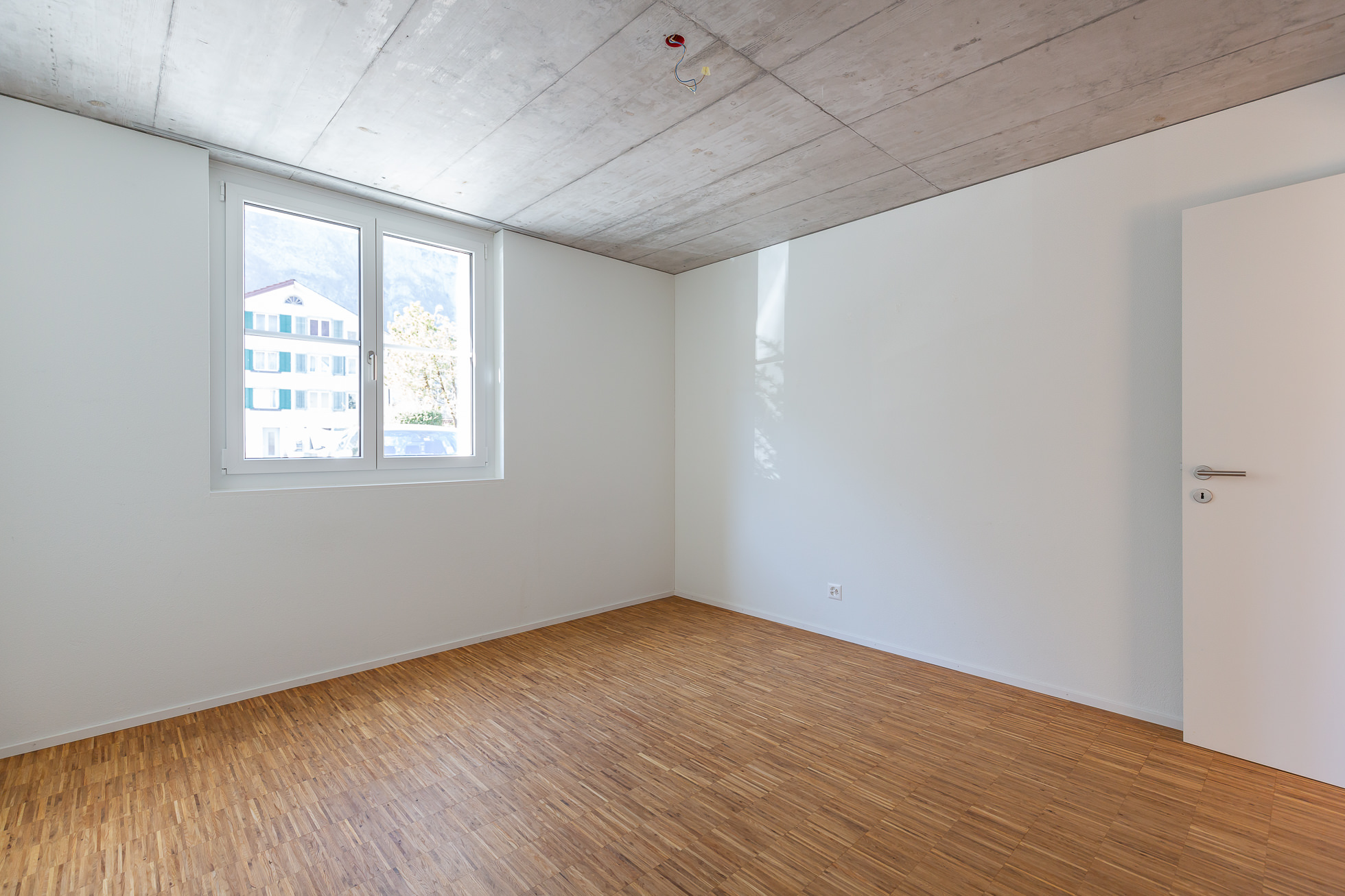 Leerer heller Raum mit Parkett und Beton-Decke