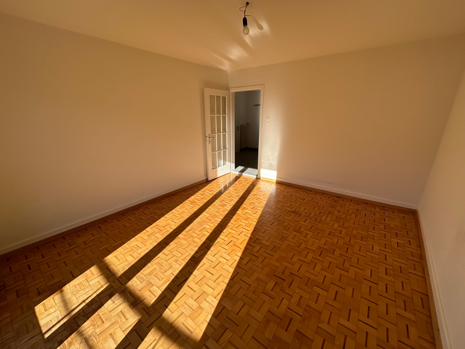 Leerer Wohnraum mit Parkett und Sonnenlicht