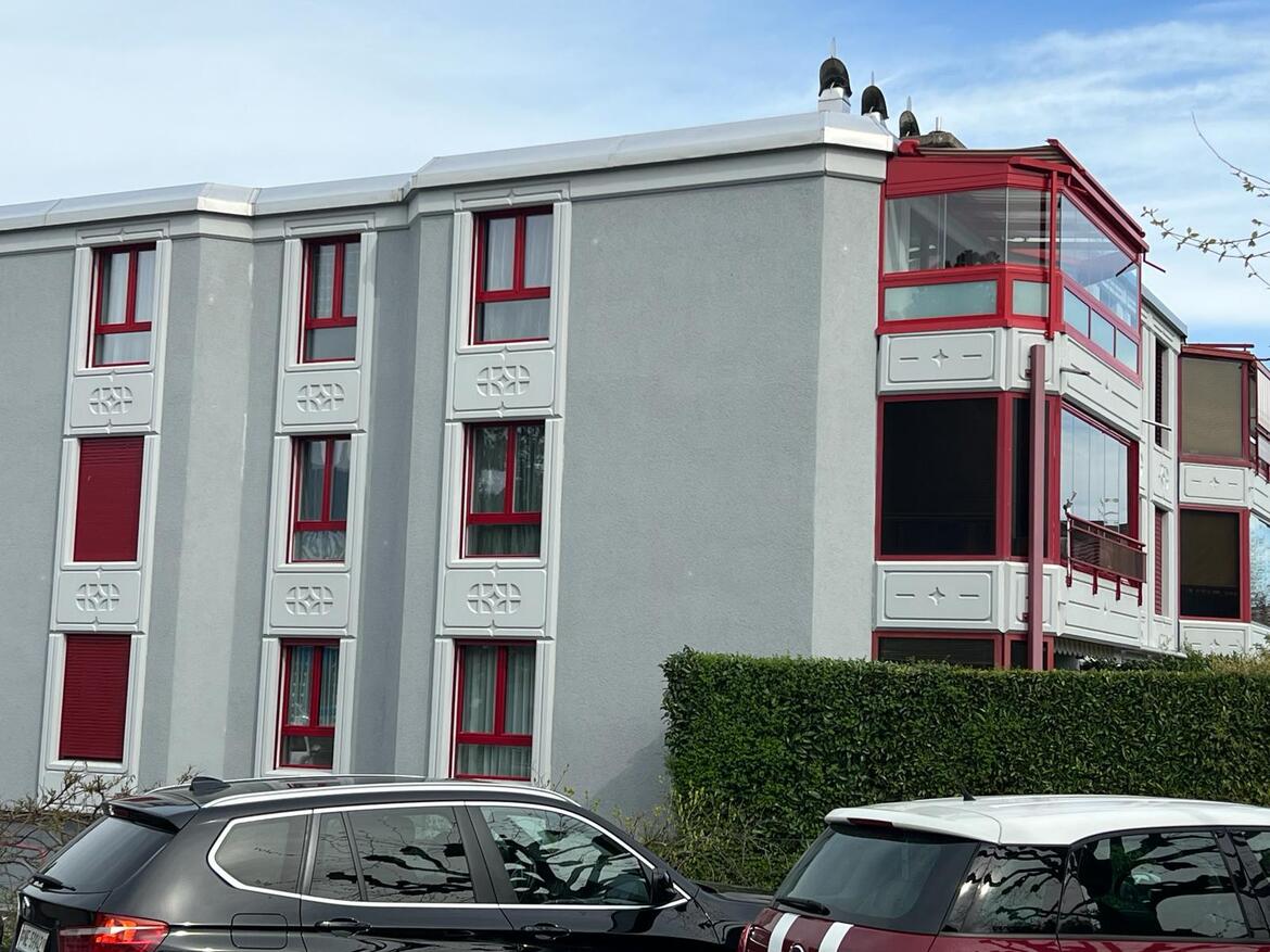 Mehrfamilienhaus mit auffälligen roten Fensterrahmen