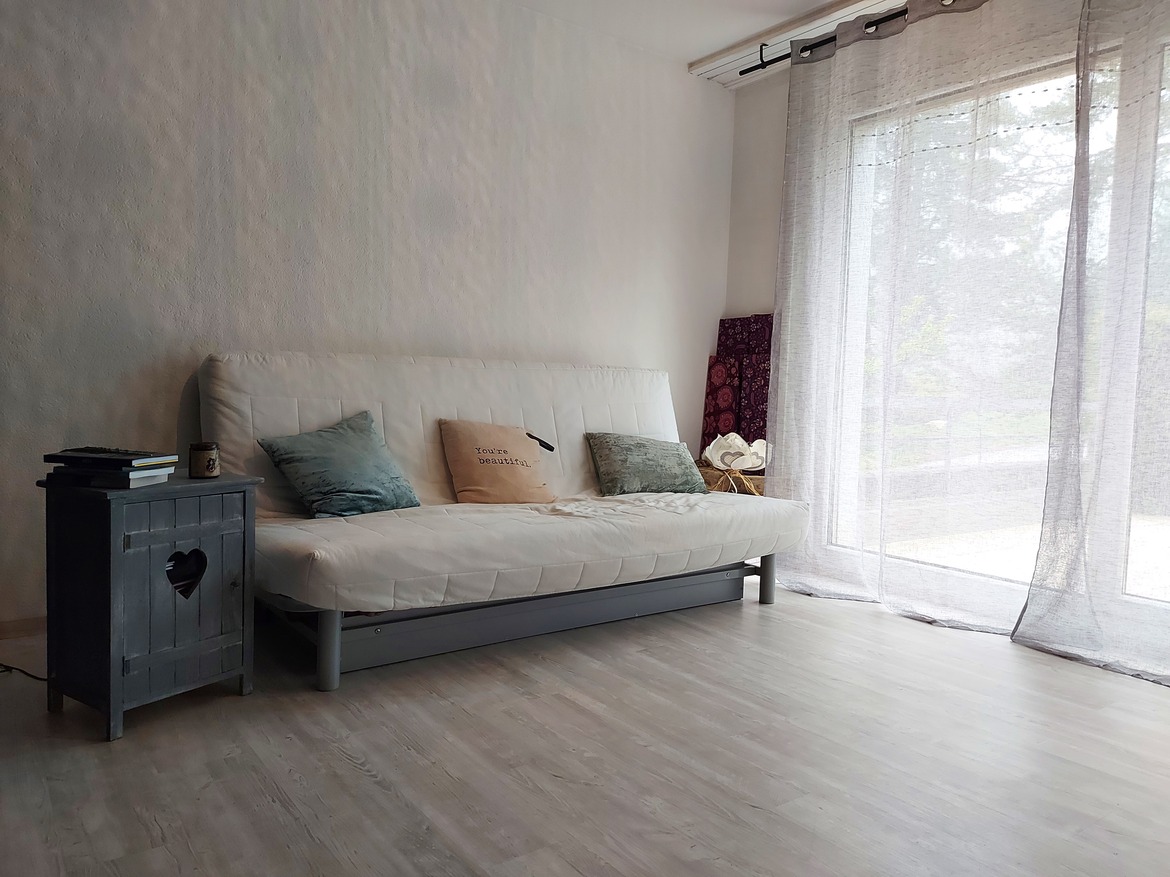 Heller Wohnraum mit Schlafsofa und Fenstervorhang