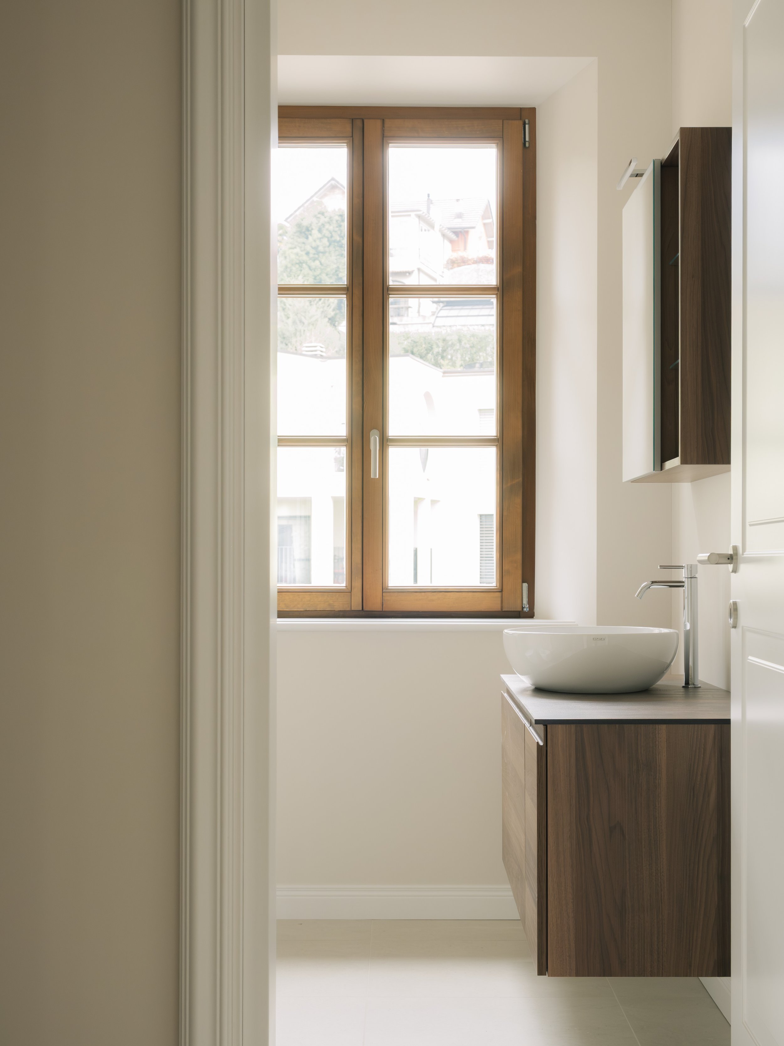 Helles Badezimmer mit Holzfenster und Waschtisch