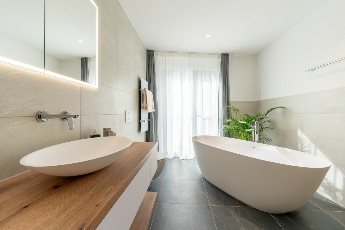 Modernes Badezimmer mit freistehender Wanne und beleuchtetem Spiegel