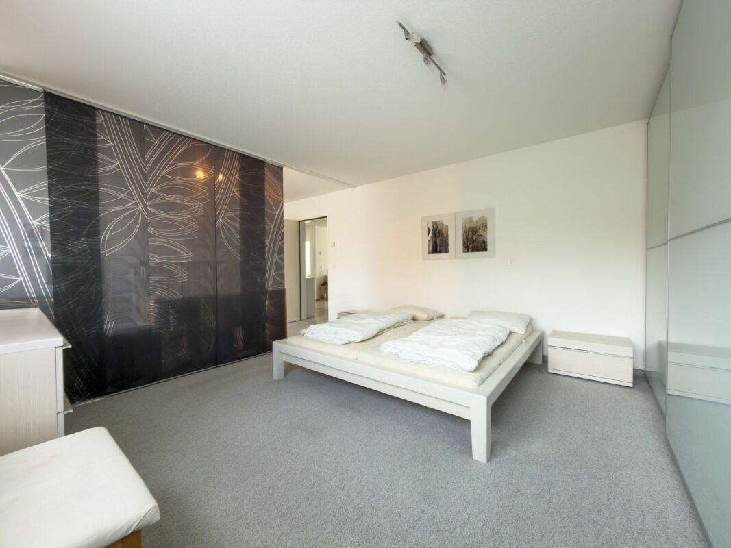 Modernes Schlafzimmer mit grauem Teppich und Schiebetürfronten
