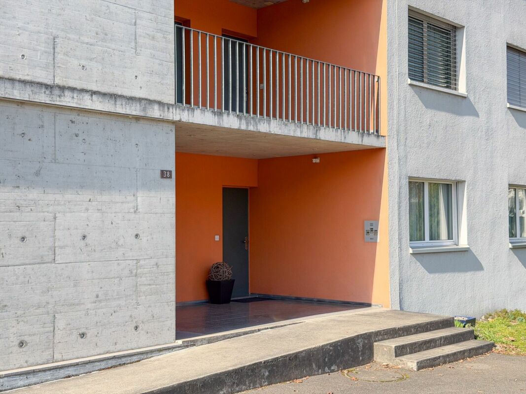 Modernes Mehrfamilienhaus-Eingangsbereich mit Beton und orangefarbener Akzentfassade