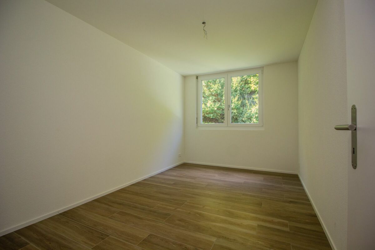 Leerer Raum mit Fenster und Holzoptikboden