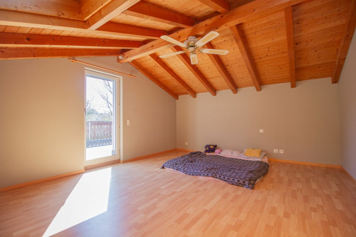 Dachzimmer mit Holzbalken und Schlafbereich