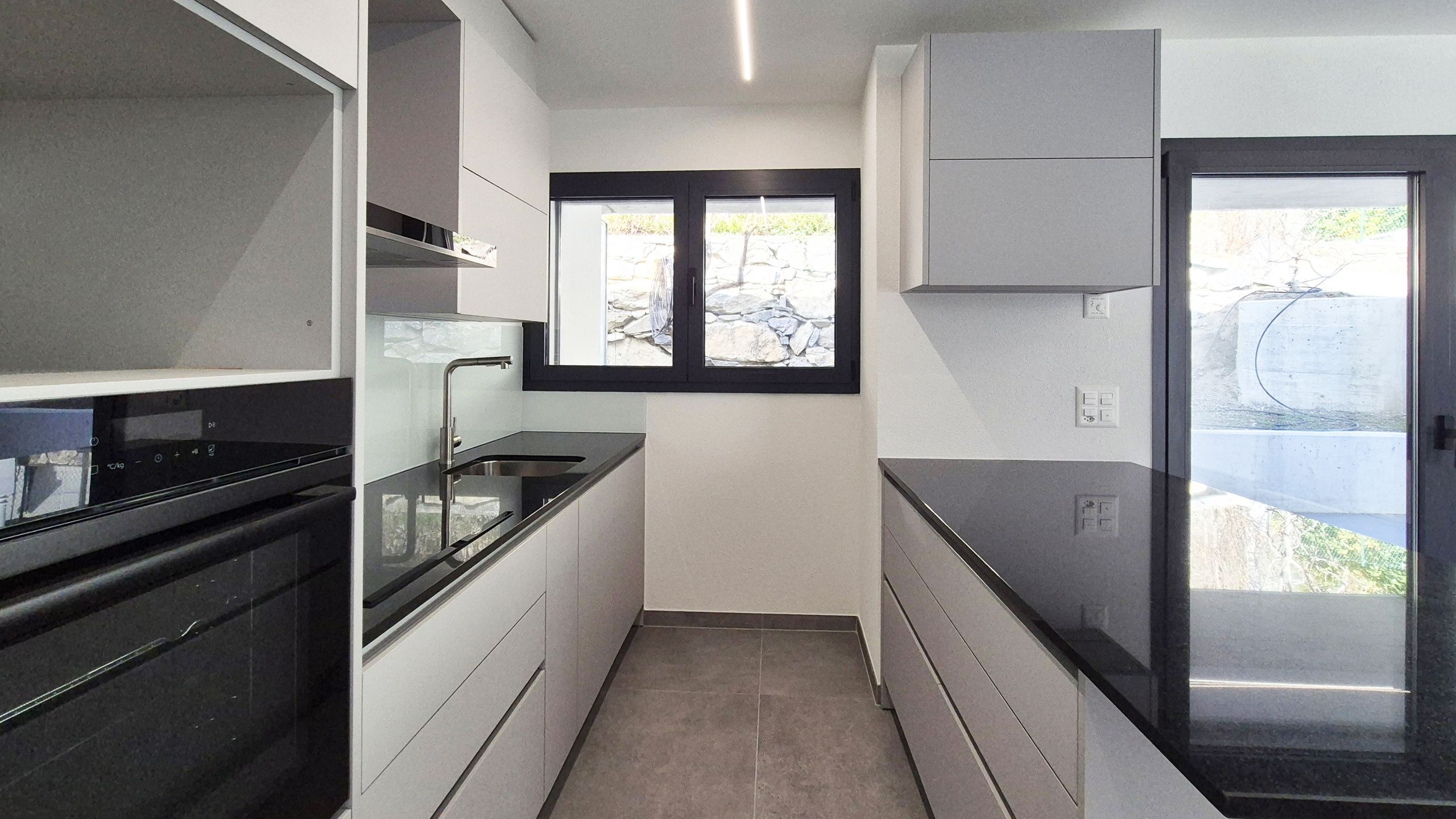 Moderne schmale Küche mit schwarzen Fensterrahmen