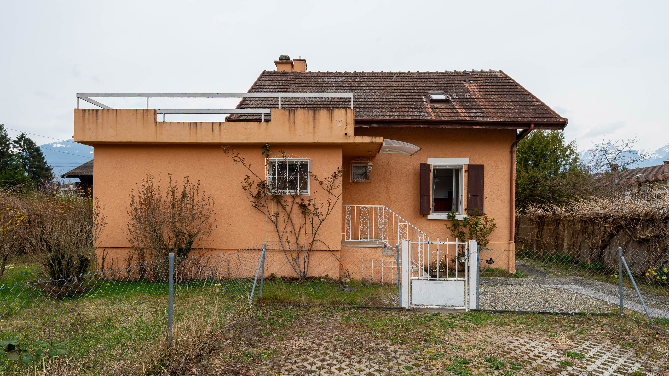 Peachfarbenes Haus mit geneigtem Dach und Vorgarten