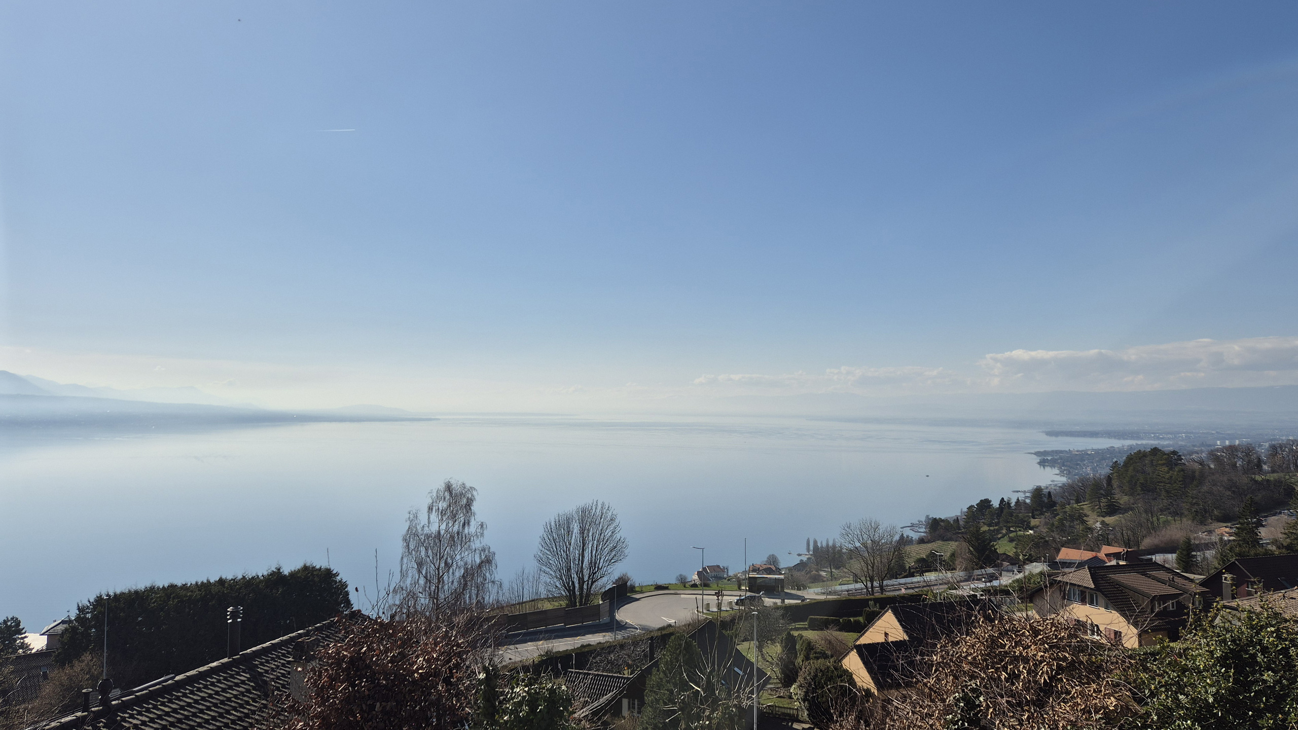 Panoramablick auf einen See mit umliegender Hügellandschaft und Wohngebiet