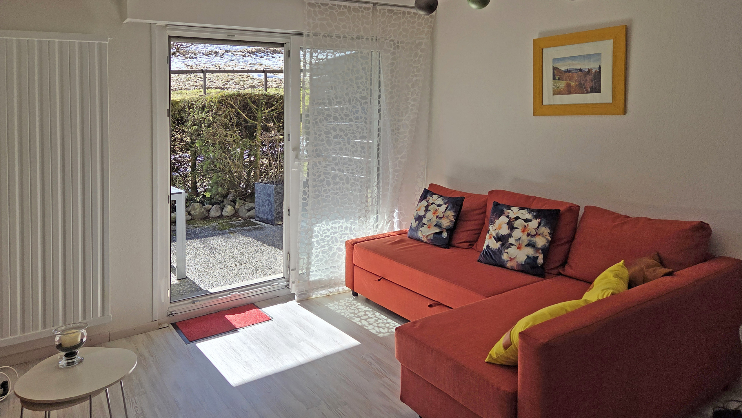 Wohnzimmer mit Terrassentür und rotem Sofa