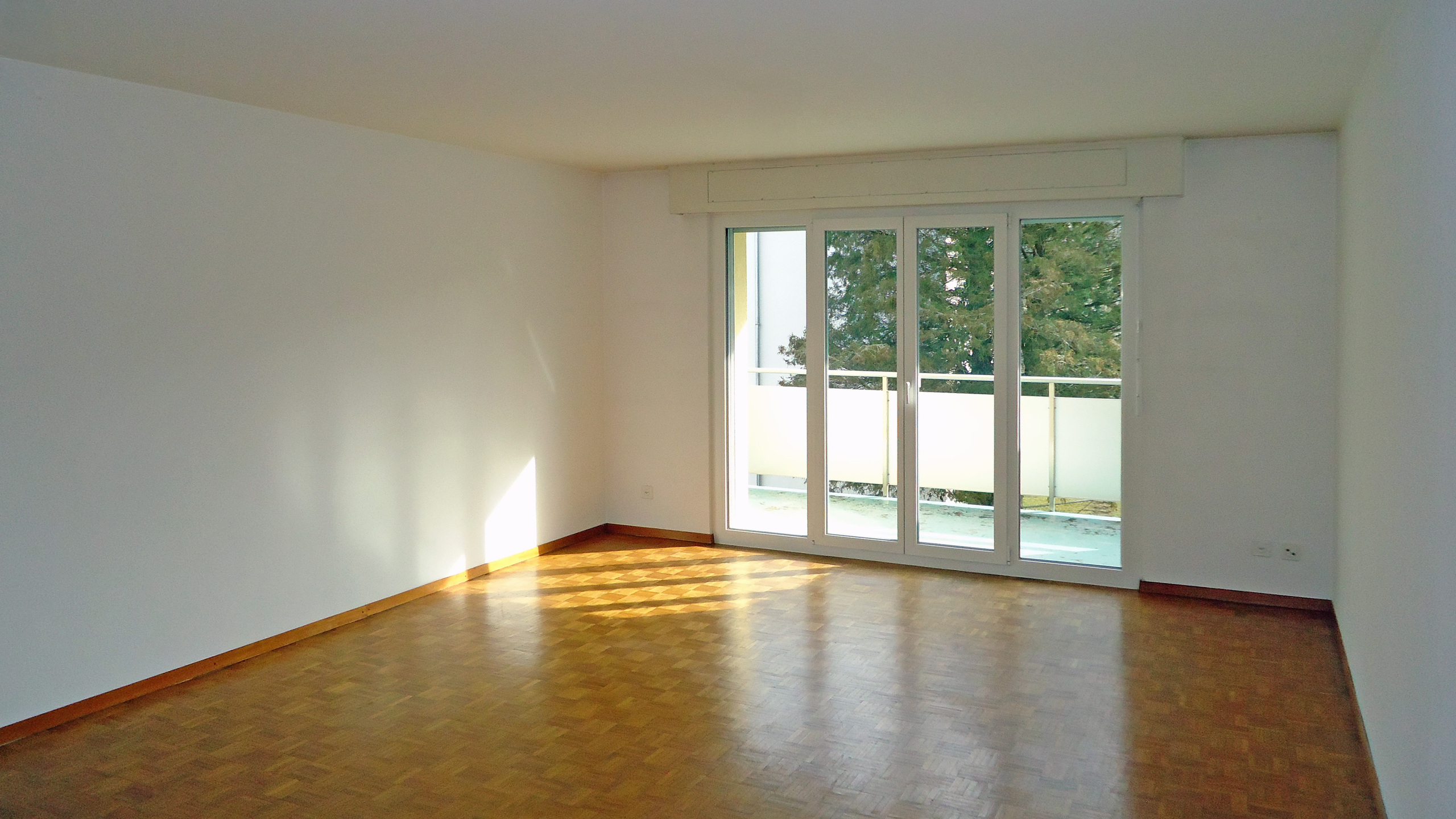 Leerer Wohnraum mit Balkonzugang