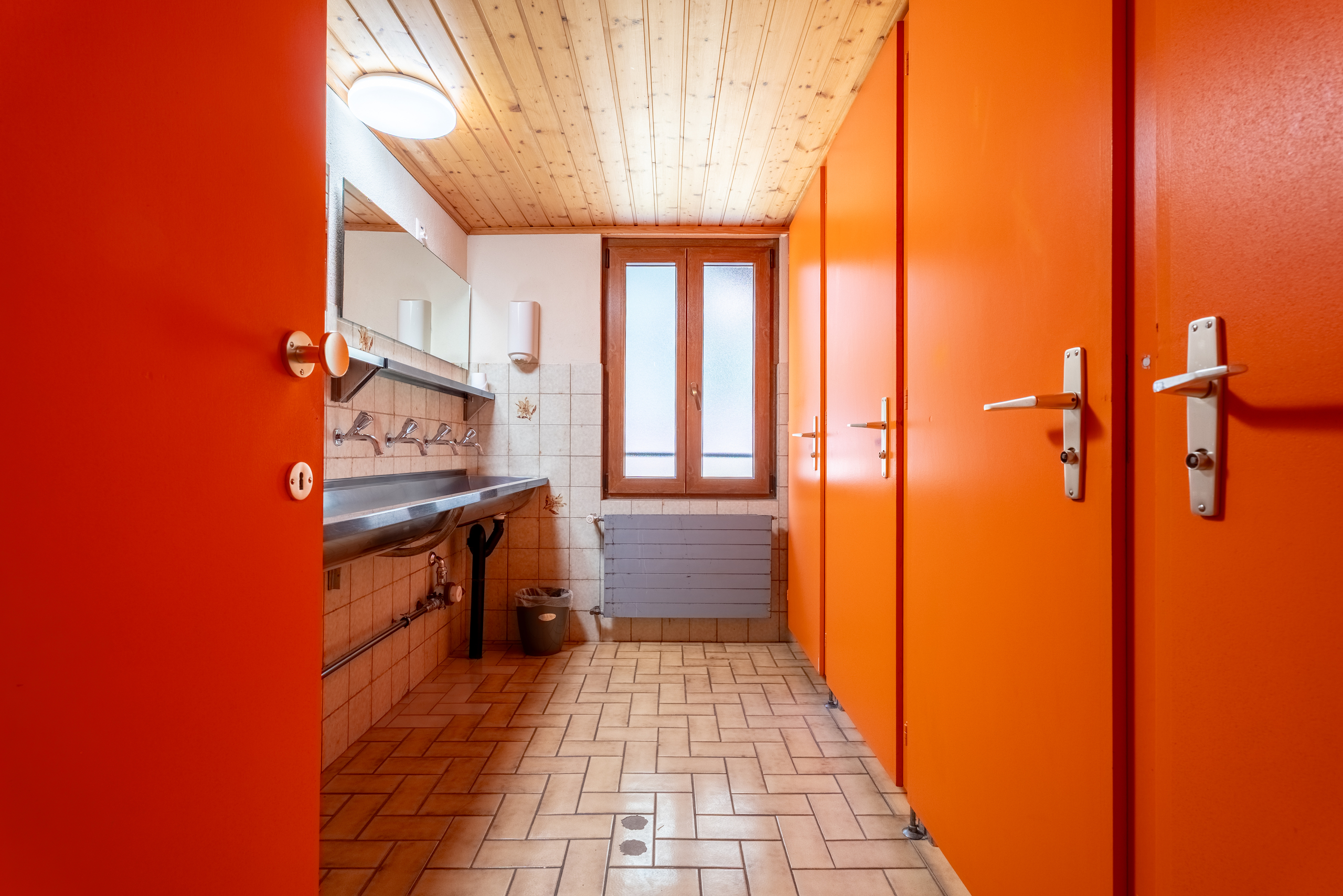 Umkleide-/Waschraum mit orangefarbenen Türen