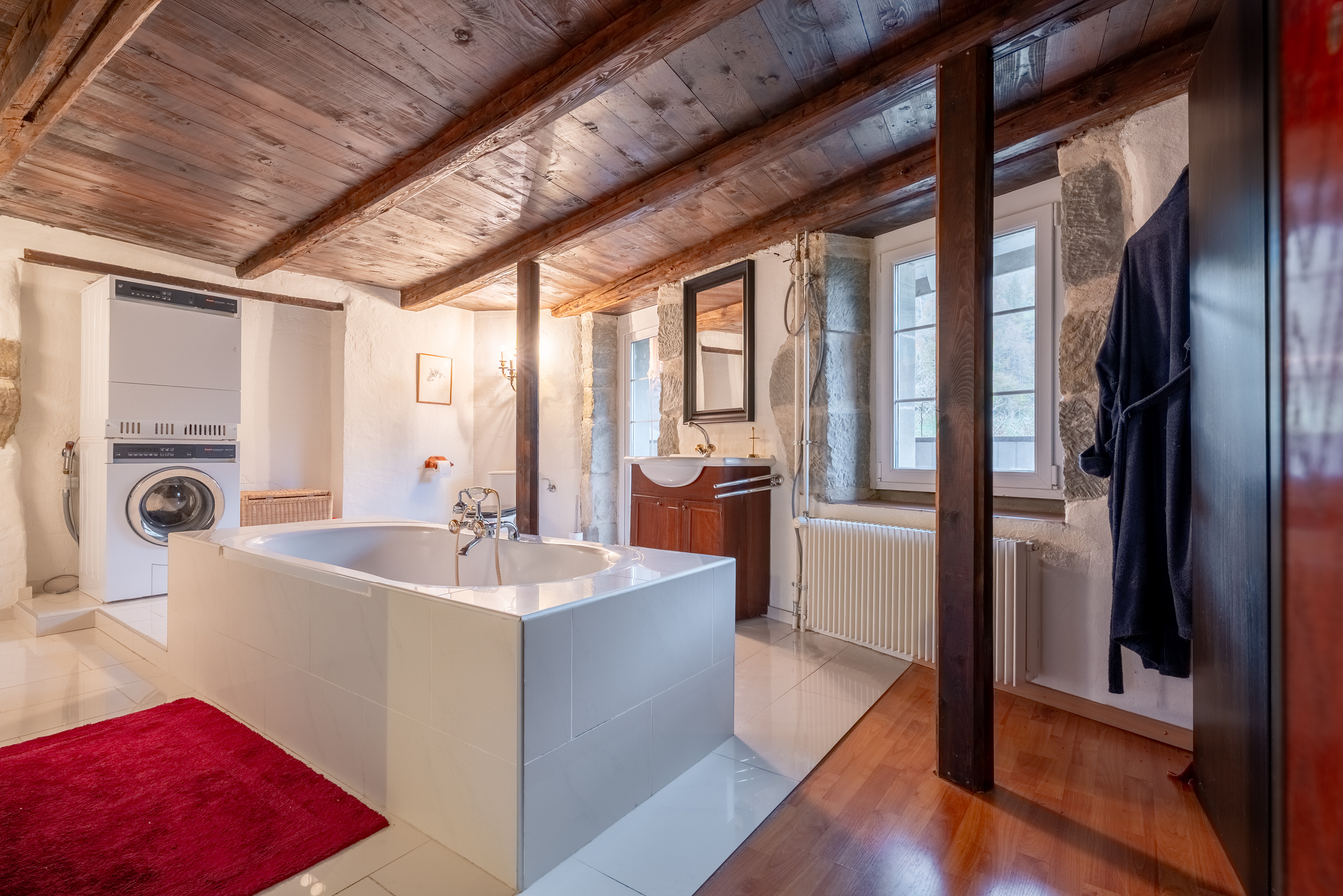 Rustikales Badezimmer mit Holzdecke und Badewanne