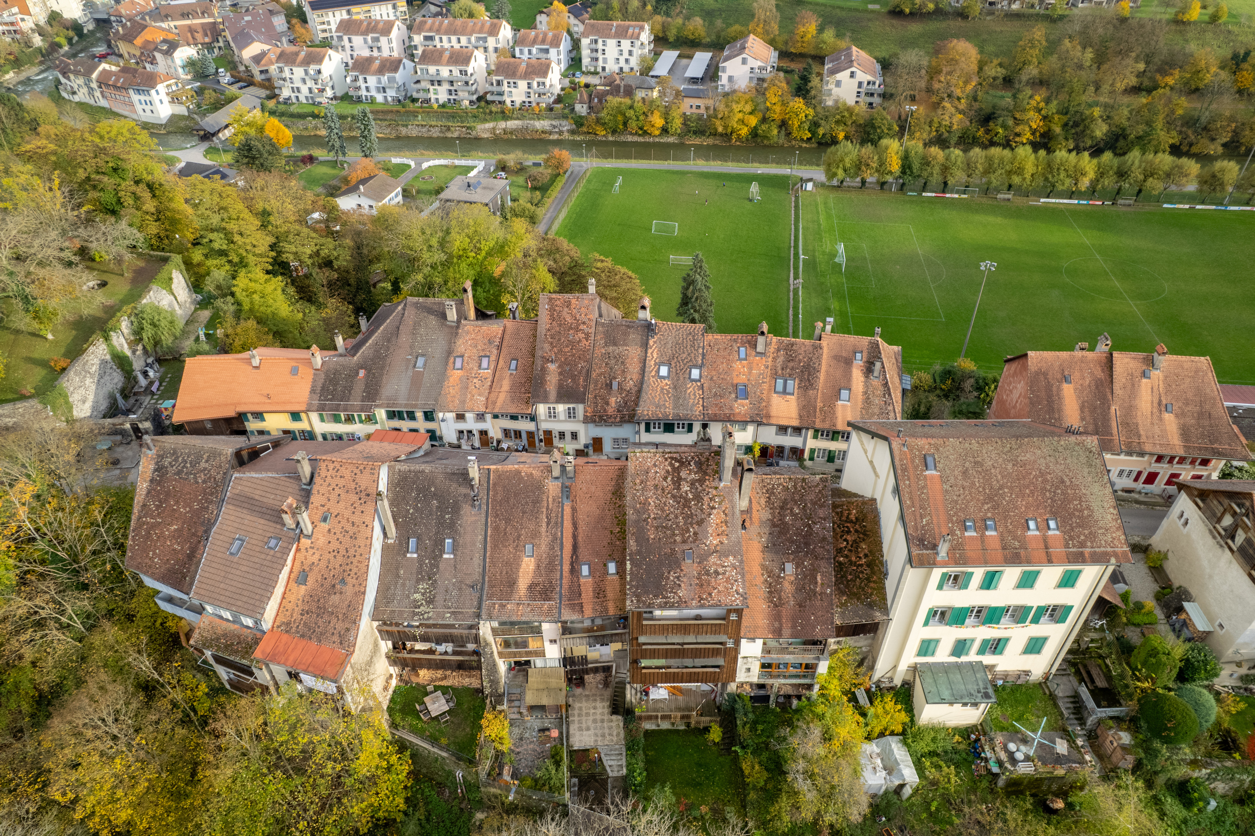 Luftaufnahme eines Wohnquartiers mit Sportplatz und Fluss